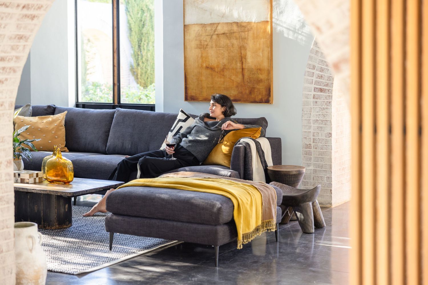 Modern living room interior with gray sectional sofa, yellow throw blanket and industrial style decor.