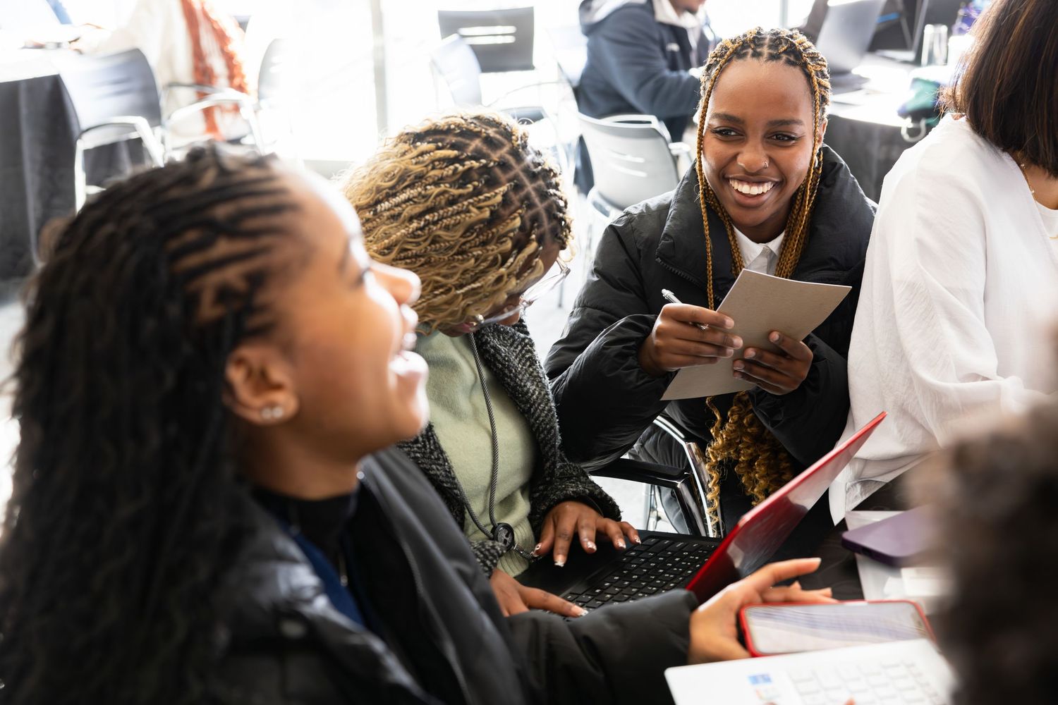 Students engage enthusiastically in collaborative group discussion around a table with study materials.