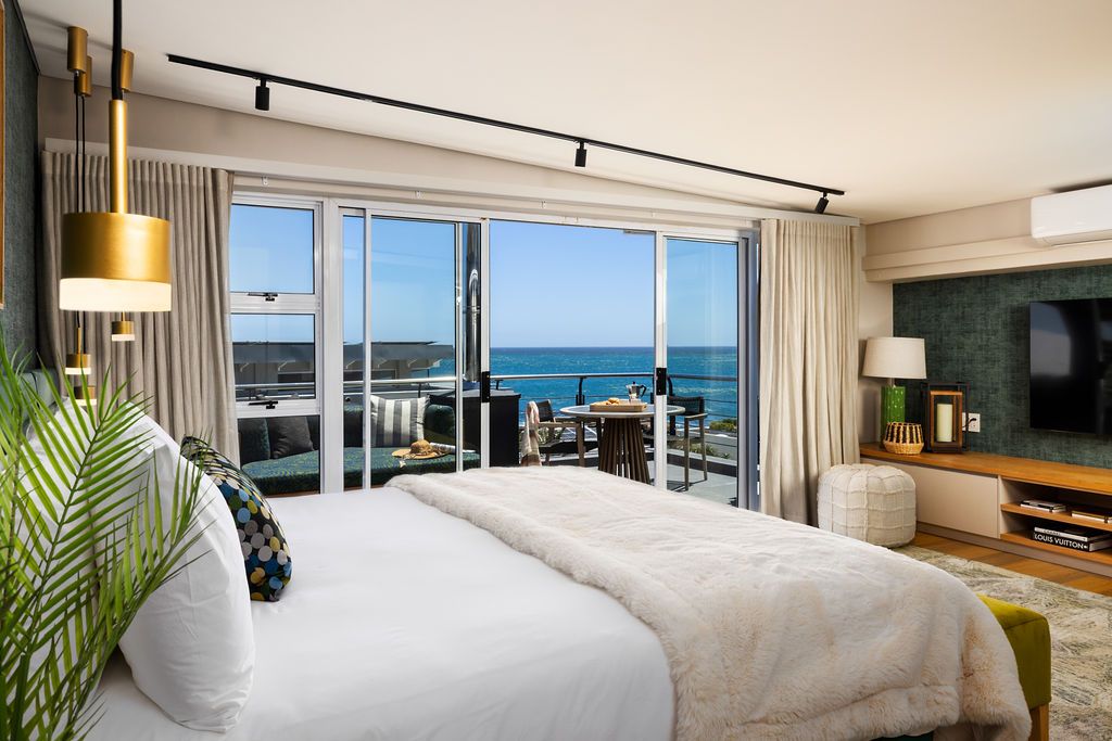 Luxurious oceanfront hotel suite with floor-to-ceiling windows showcasing stunning beach views and modern coastal decor.