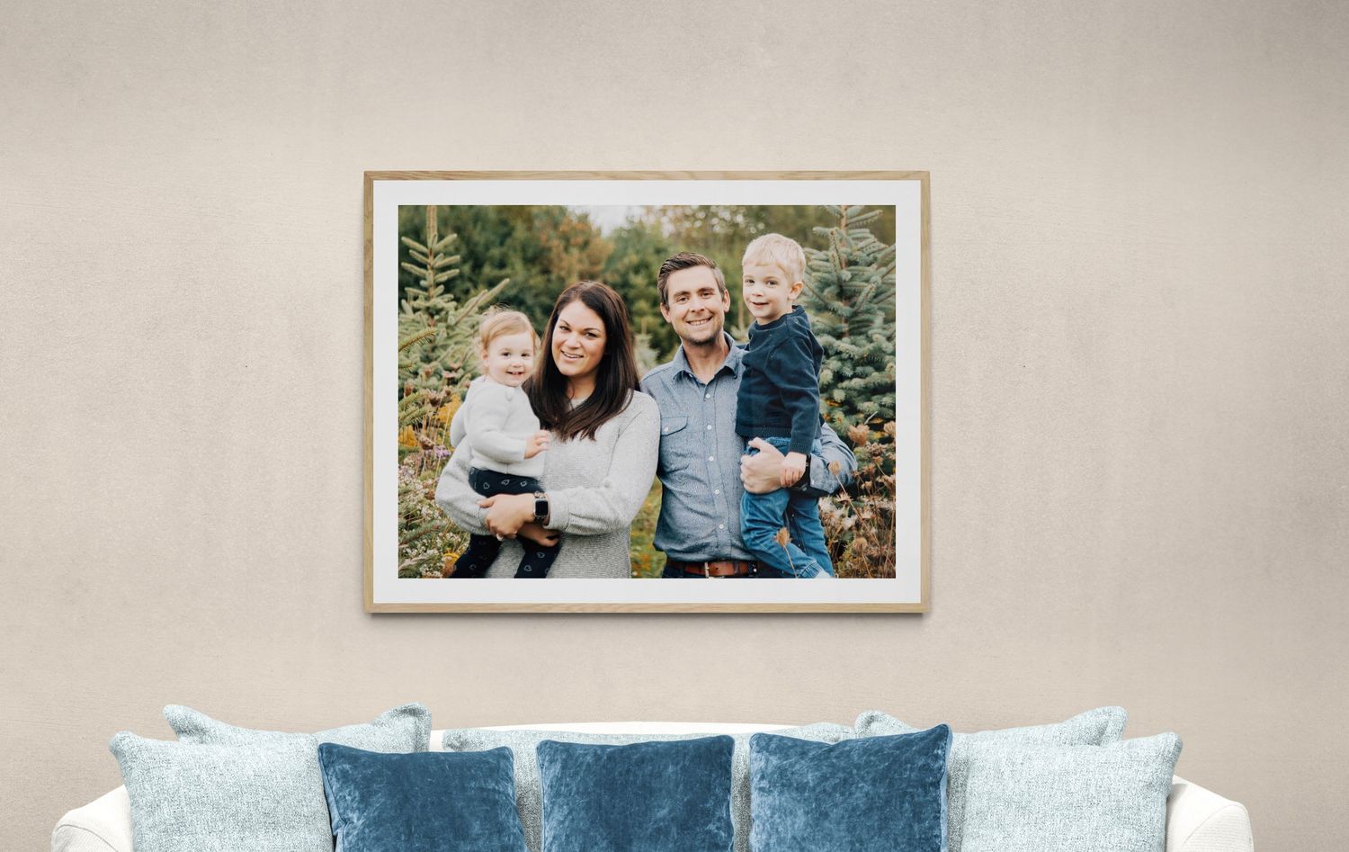 Gallery wall display with framed photos and blue accent pillows in neutral living room.