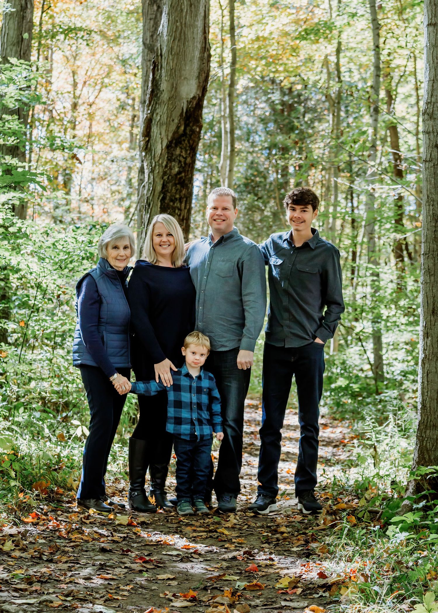 Family group standing together in autumn woods with fallen leaves on the ground.