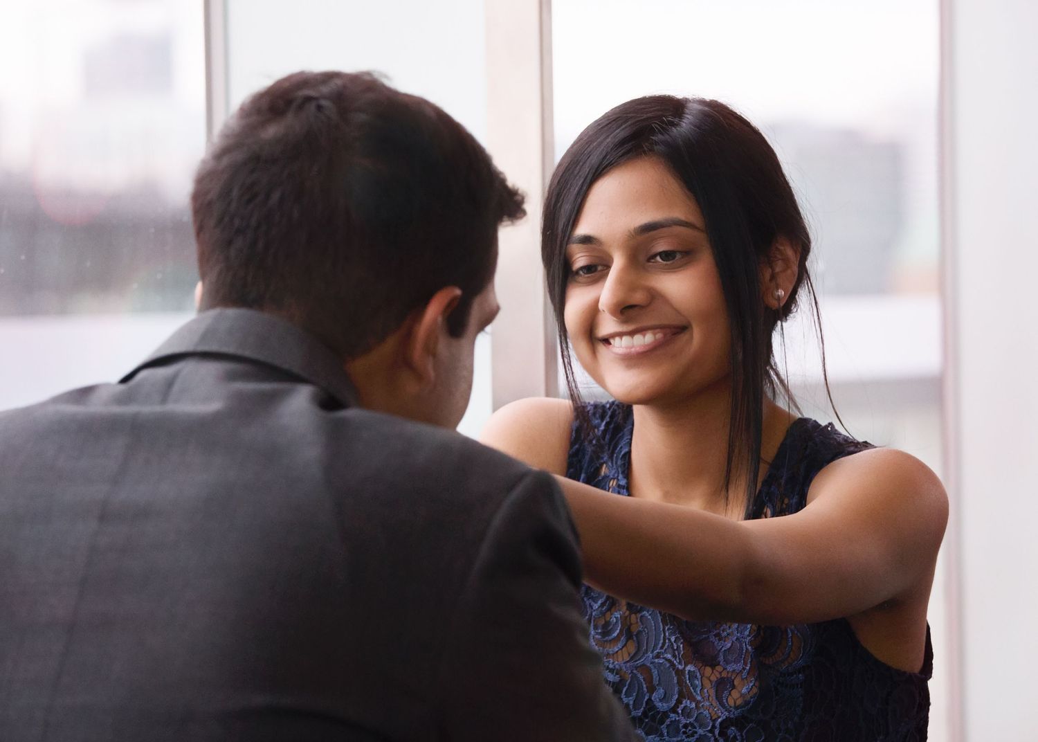 A romantic couple shares tender moments together near large windows in a sequence of intimate photographs.