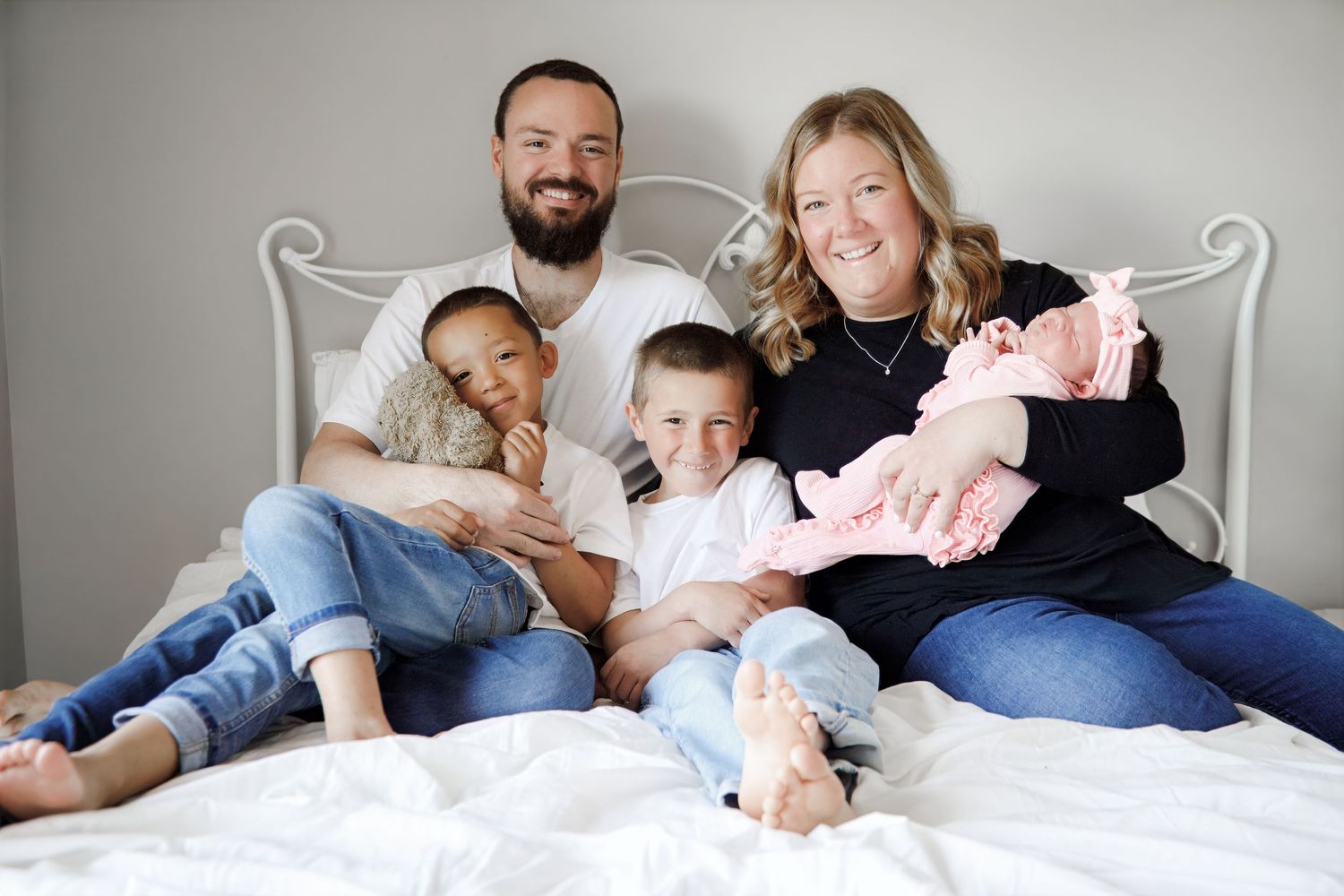 Casual family bonding session captured on comfortable white bed.