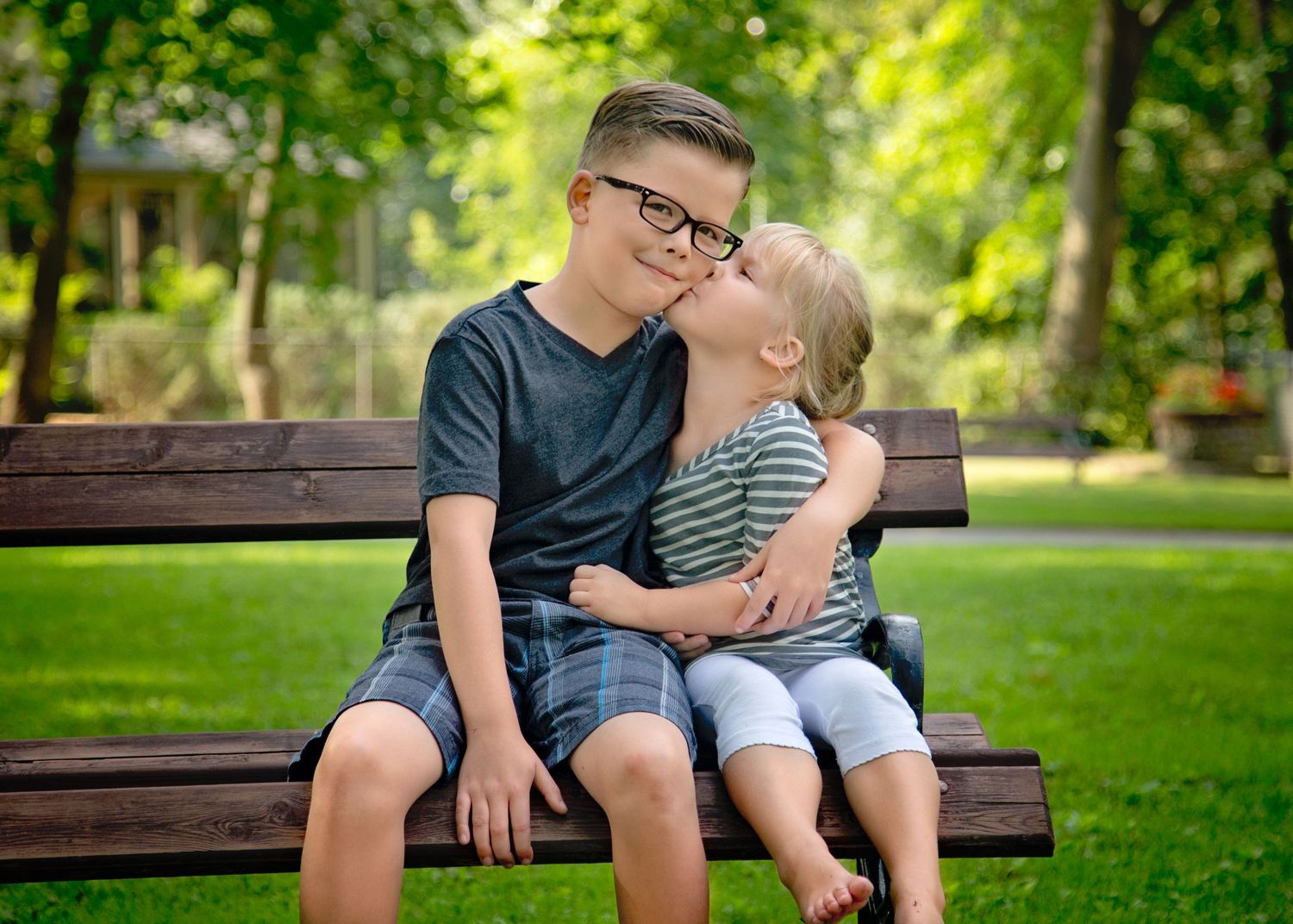 Family portrait session on park bench with natural green background.