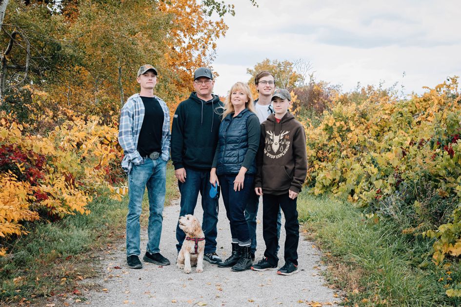 A group stands together on a nature path surrounded by golden autumn foliage and fallen leaves.