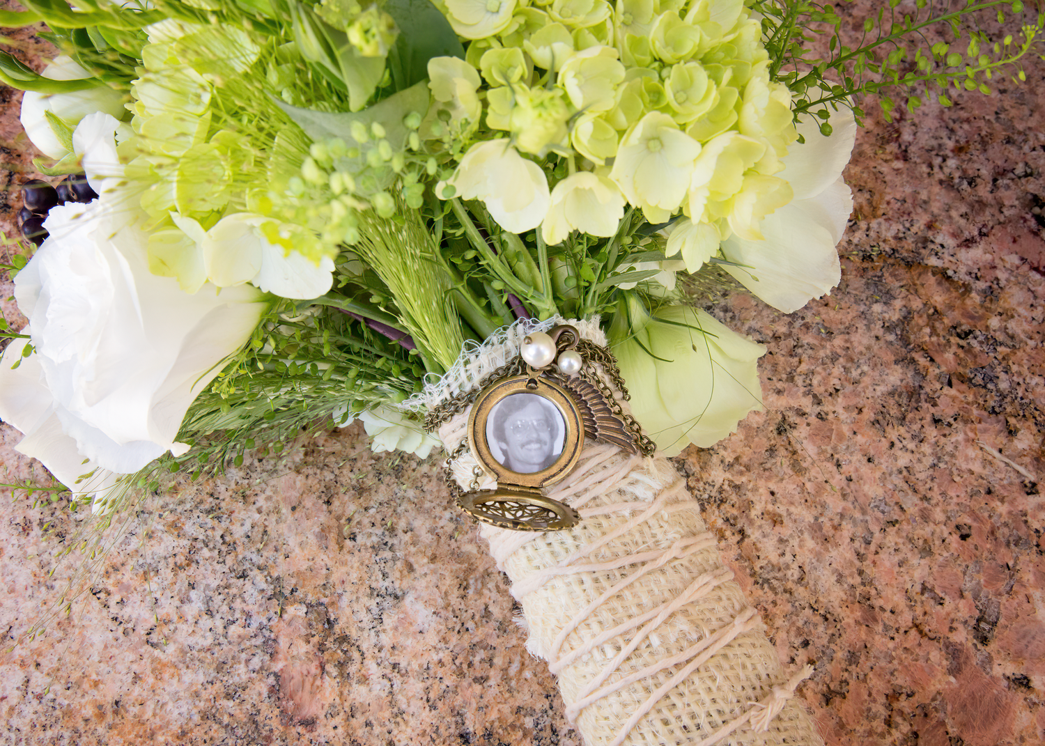 Fresh green lettuce heads and white flowers arranged with burlap ribbon on a rustic stone surface.