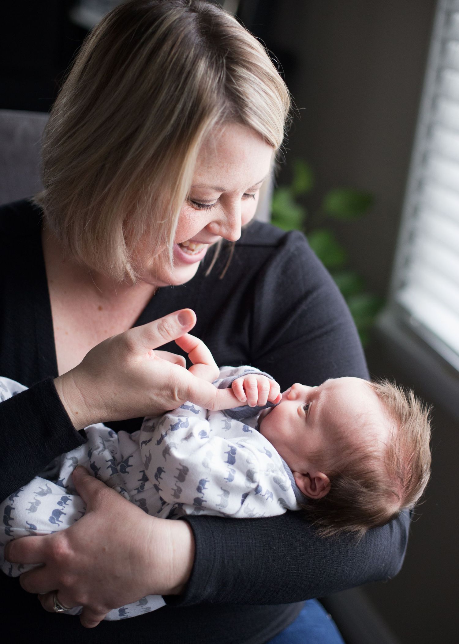 A tender moment showing someone holding and nurturing an infant wrapped in patterned swaddle.