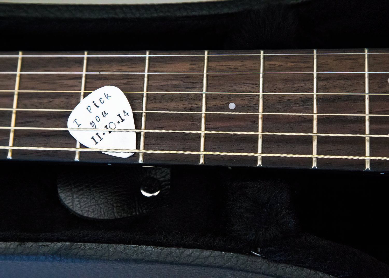 Close-up view of a guitar neck with frets and strings against a dark background.