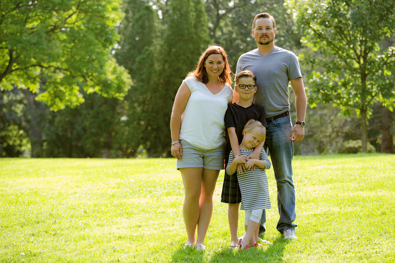 Happy family enjoying a sunny day outside together walking on green grass in a peaceful park setting.