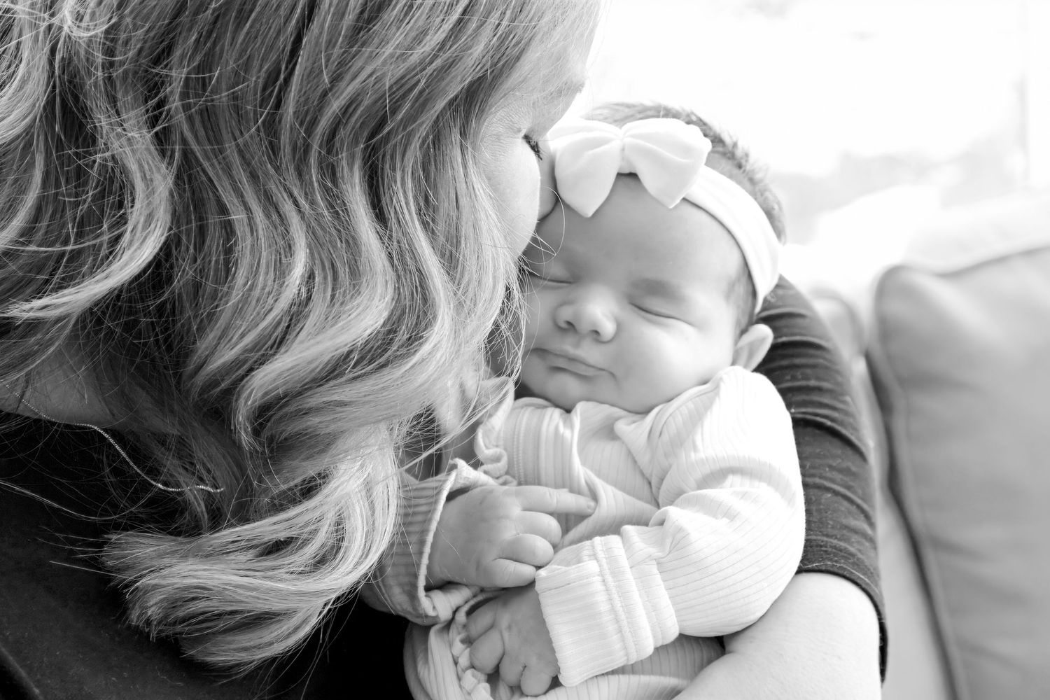 A series of black and white photos showing tender moments between a parent and baby lying together.