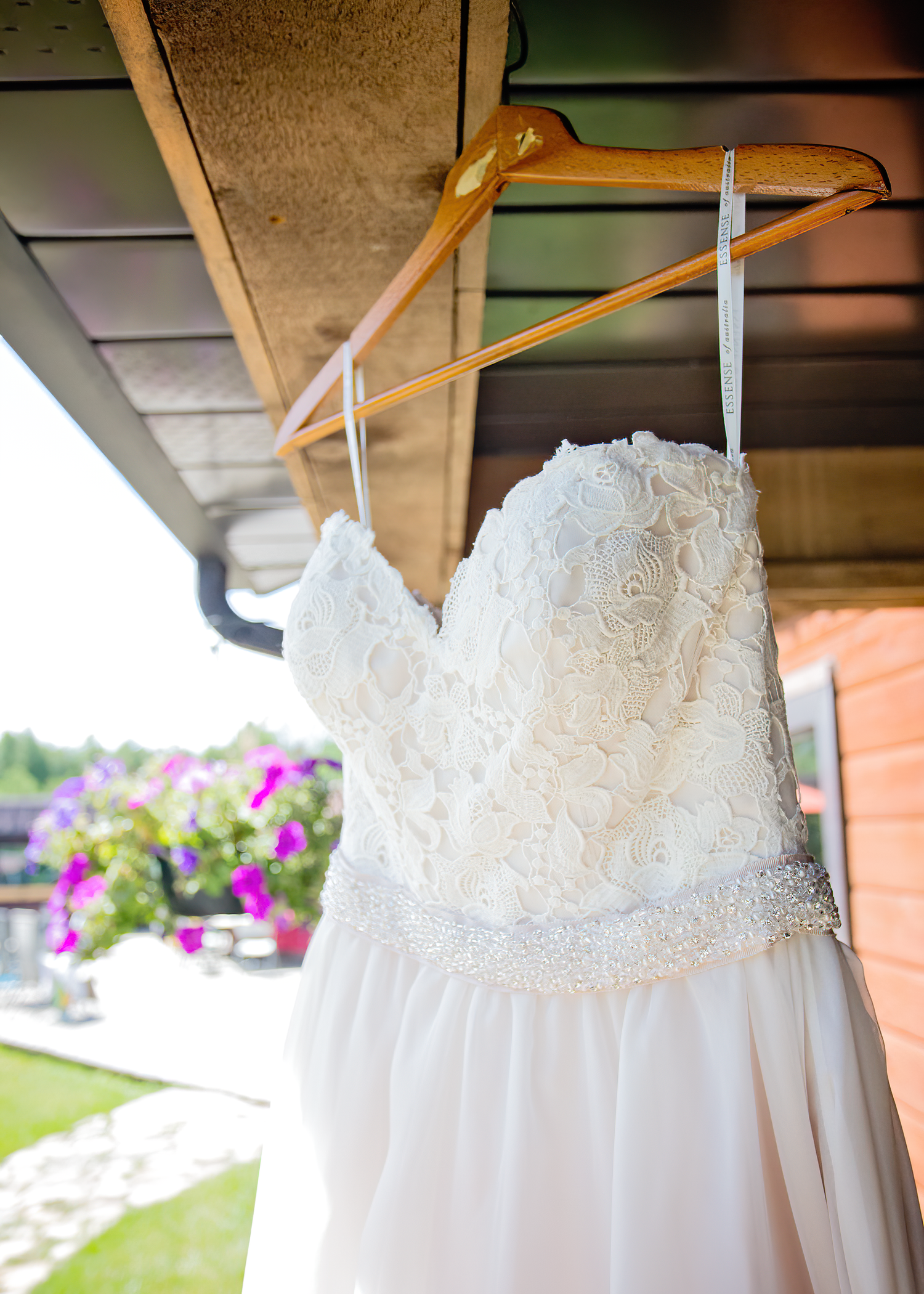 White lace wedding dress details shown hanging on wooden hangers with delicate beading and embroidery patterns.