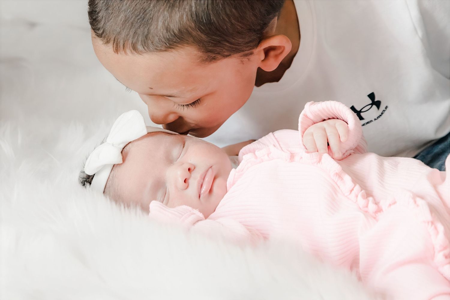A newborn baby wearing pink sleeps peacefully while being photographed from different angles.