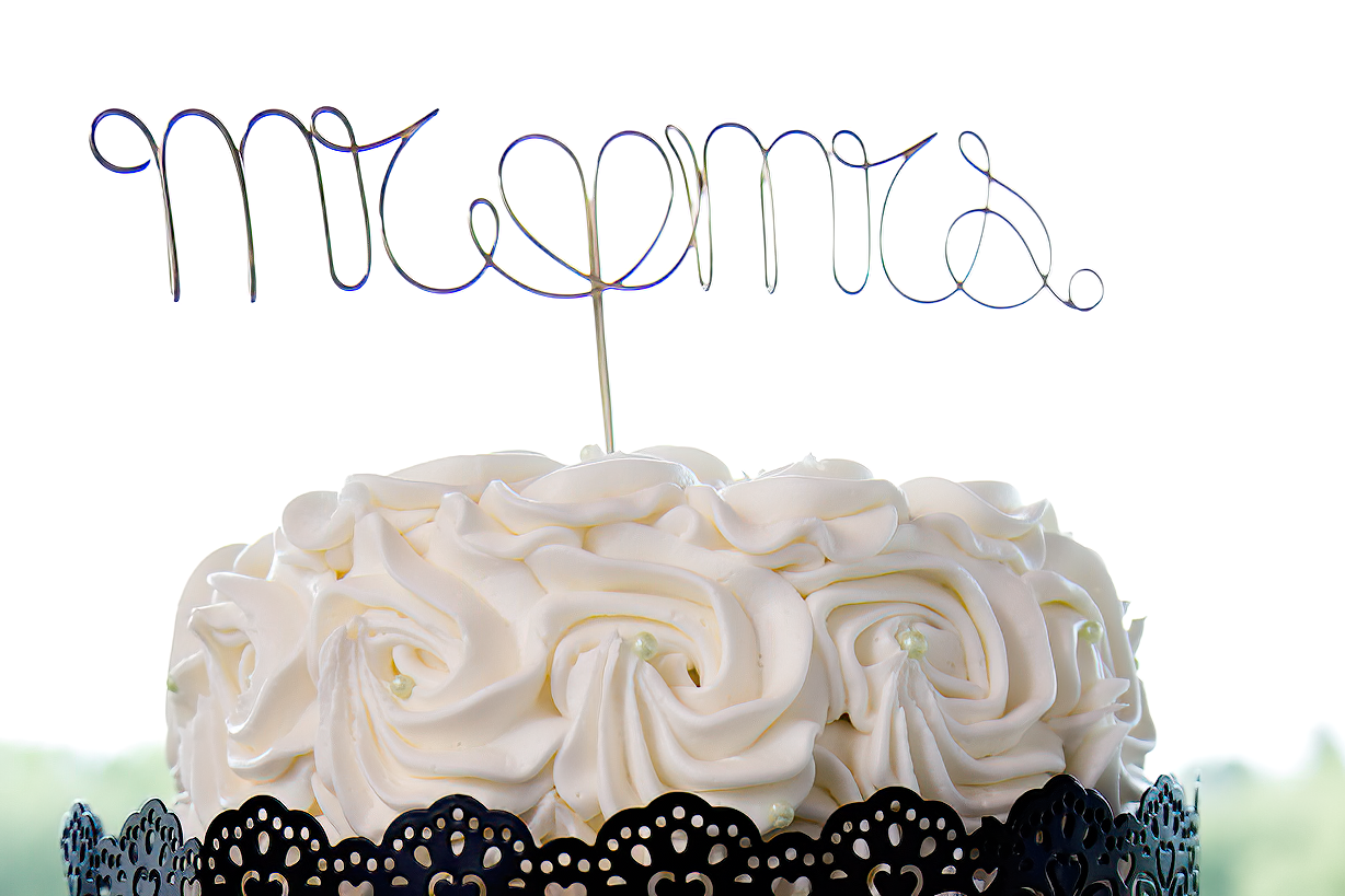 Elegant white wedding cupcakes decorated with buttercream frosting and black lace trim on a tiered display stand.