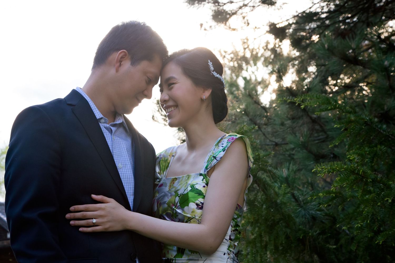 Romantic couple shares intimate moments in a garden setting during sunset photo session.
