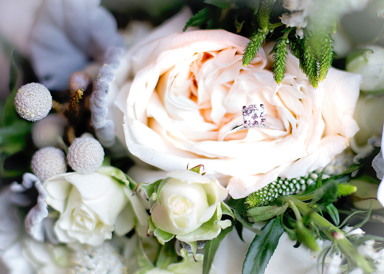 Delicate peach and white roses arranged with silvery foliage and small white berries in an elegant floral display.