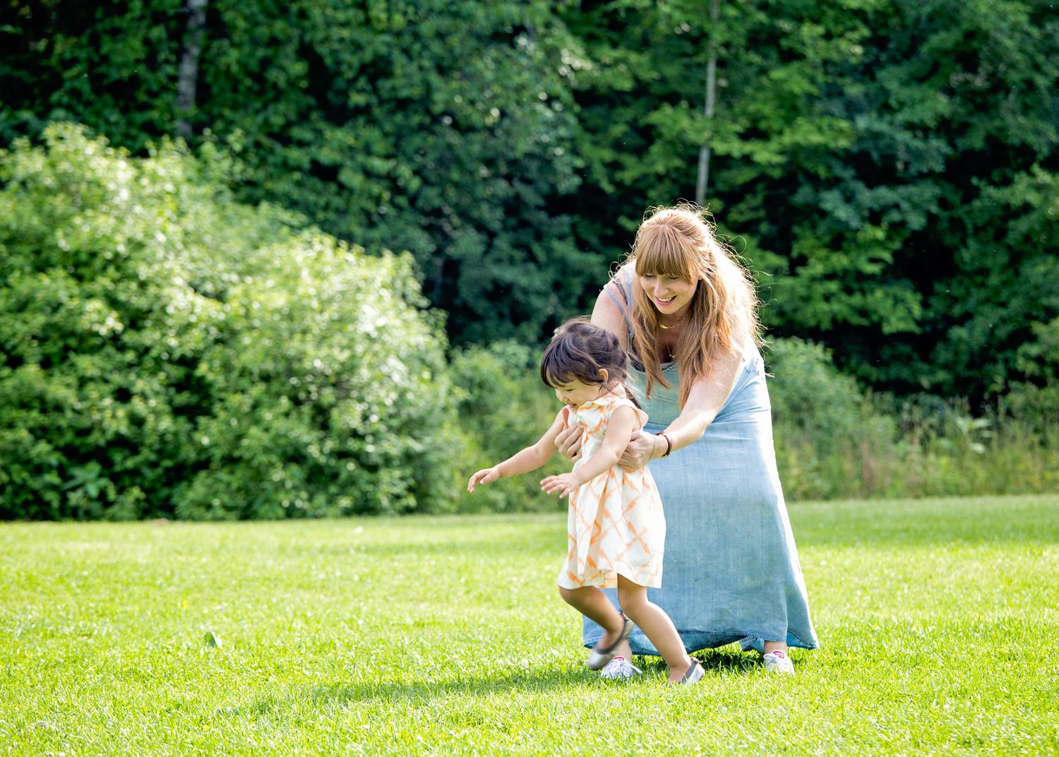 Summer family photo session in park with green trees backdrop.
