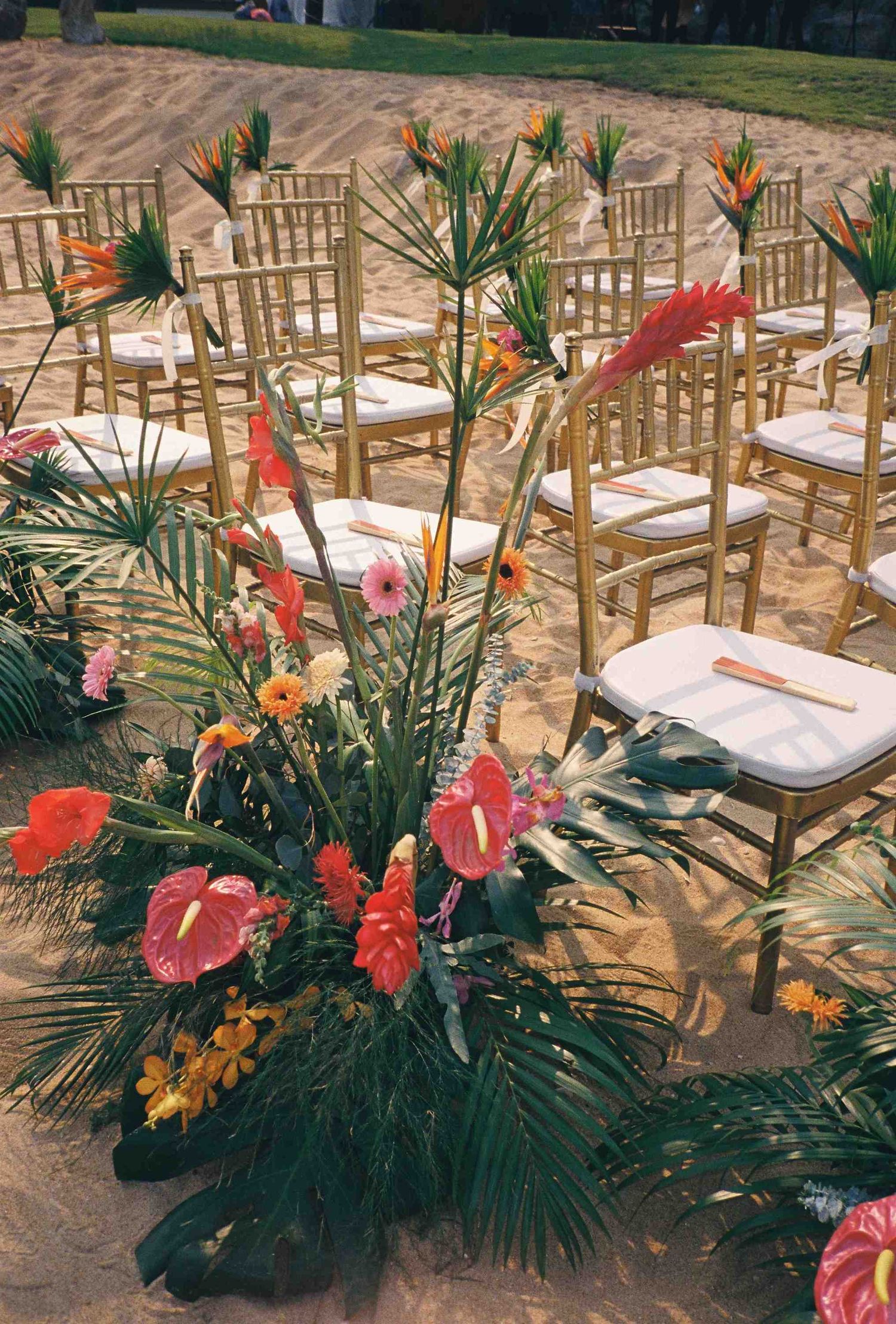 Lang Co wedding ceremony: tropical floral arrangements decorate gold chiavari chairs set up for an outdoor ceremony, by AnhVuWedding.