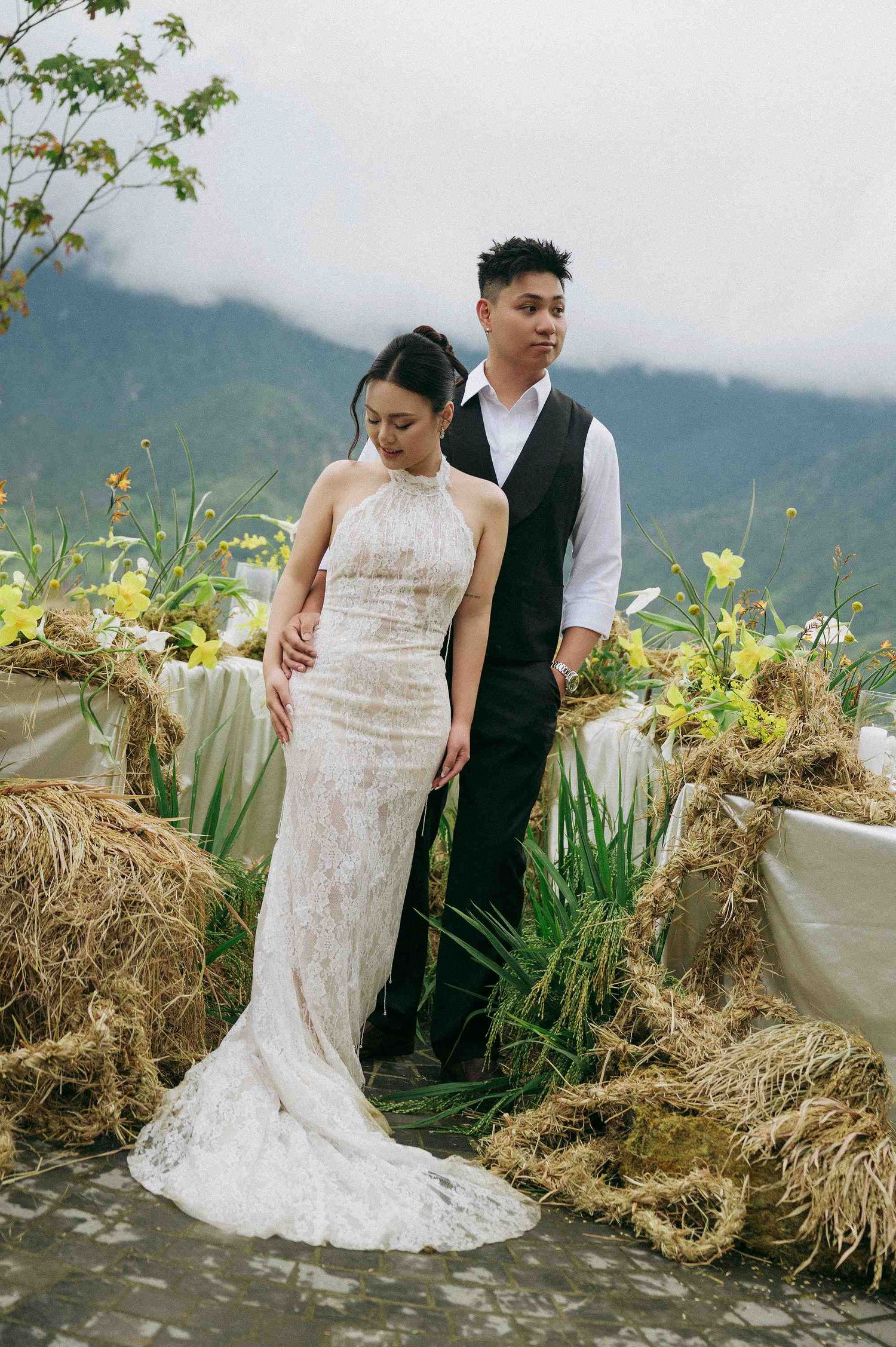 wedding: wedding couple posing in formal attire against misty mountain backdrop with decorative hay bales, by AnhVuWedding.