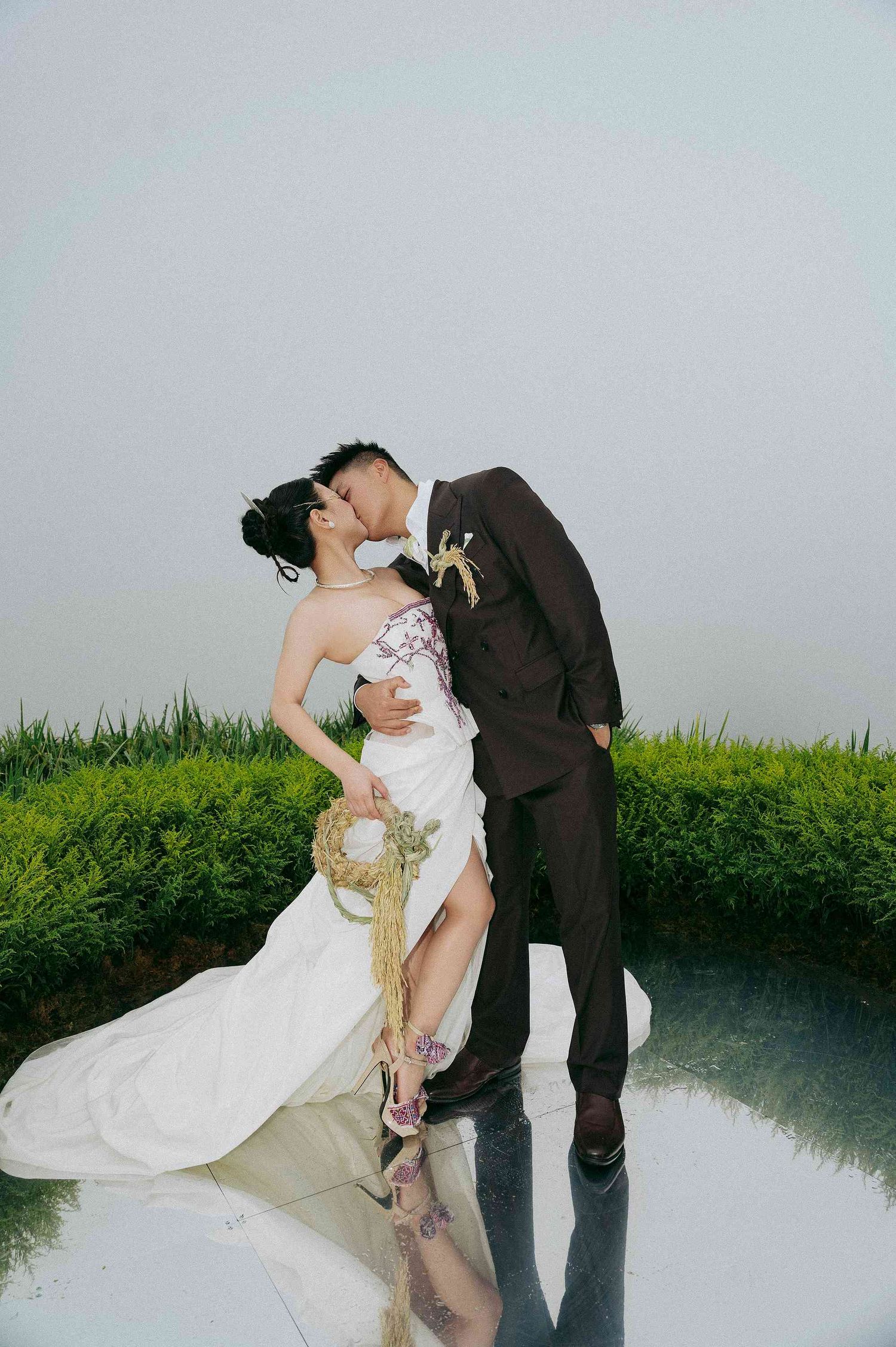 wedding: wedding couple poses together on a reflective surface surrounded by green grass, by AnhVuWedding.