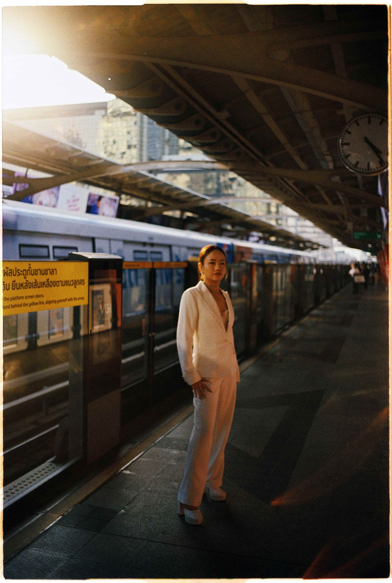 Saigon pre-wedding: person in an all-white outfit stands alone on a train platform with sunglasses, by AnhVuWedding.