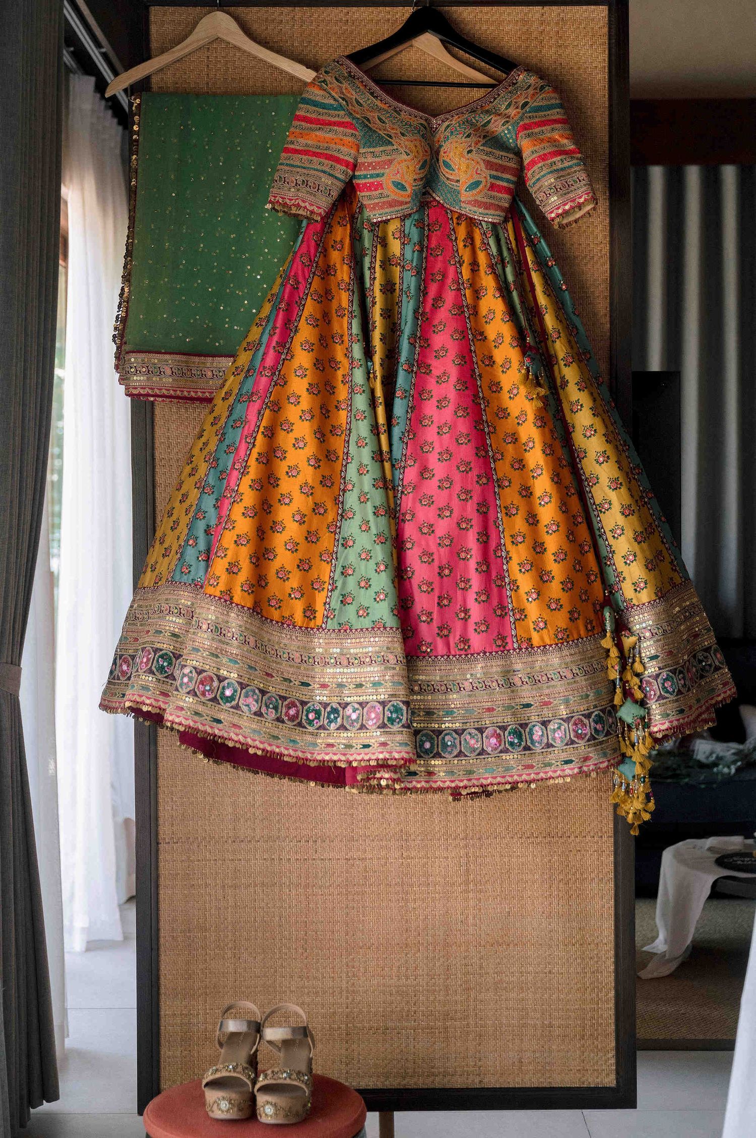 Colorful multicolor patchwork lehenga choli with embroidered border hanging on display with green dupatta.