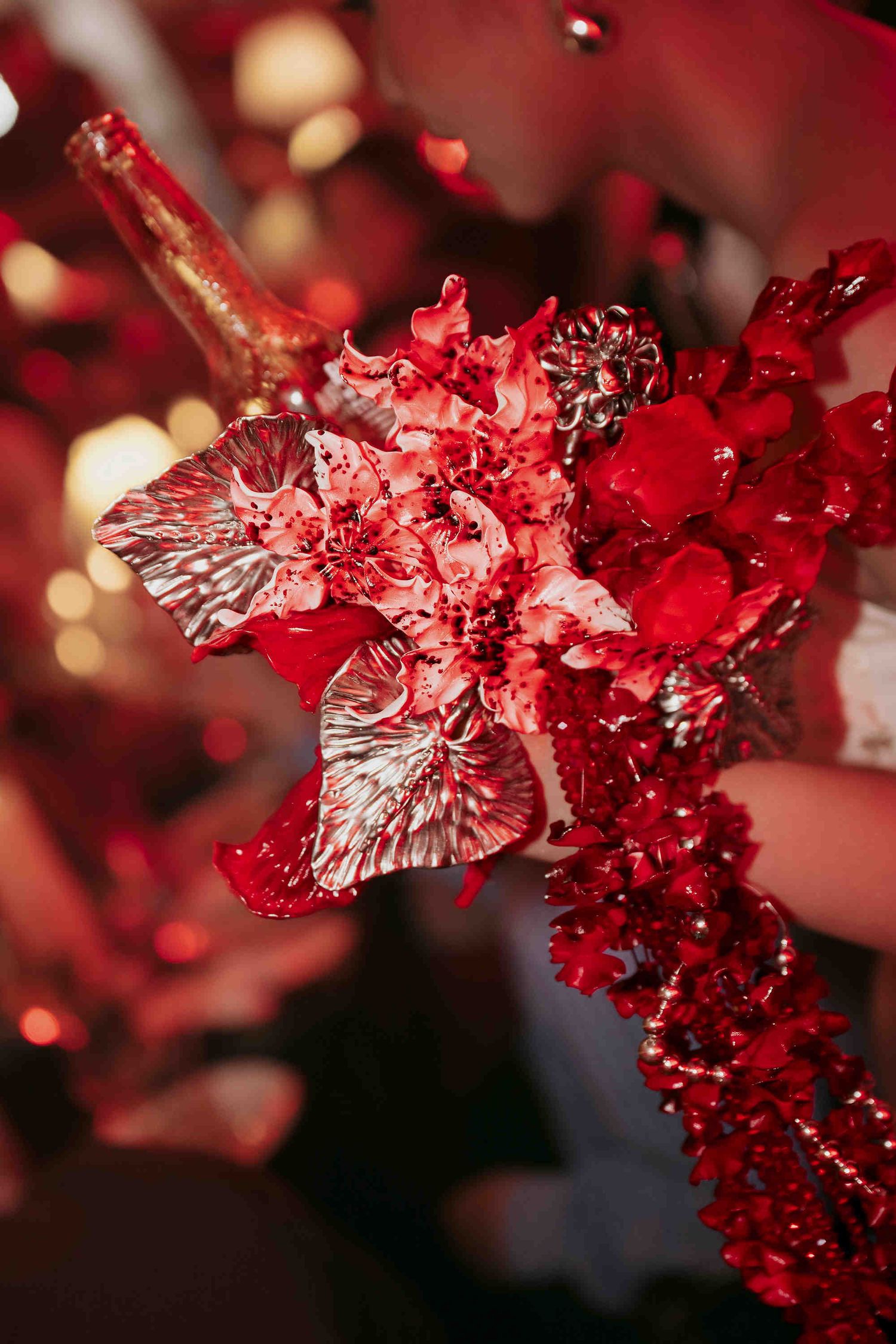 Red and silver metallic floral arrangement with glittery decorations at a festive event.