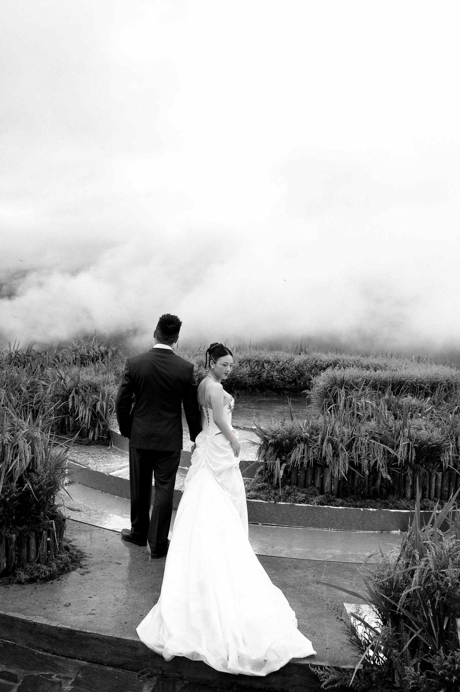 wedding: wedding couple walks along scenic mountain path surrounded by tall grass and fog, by AnhVuWedding.