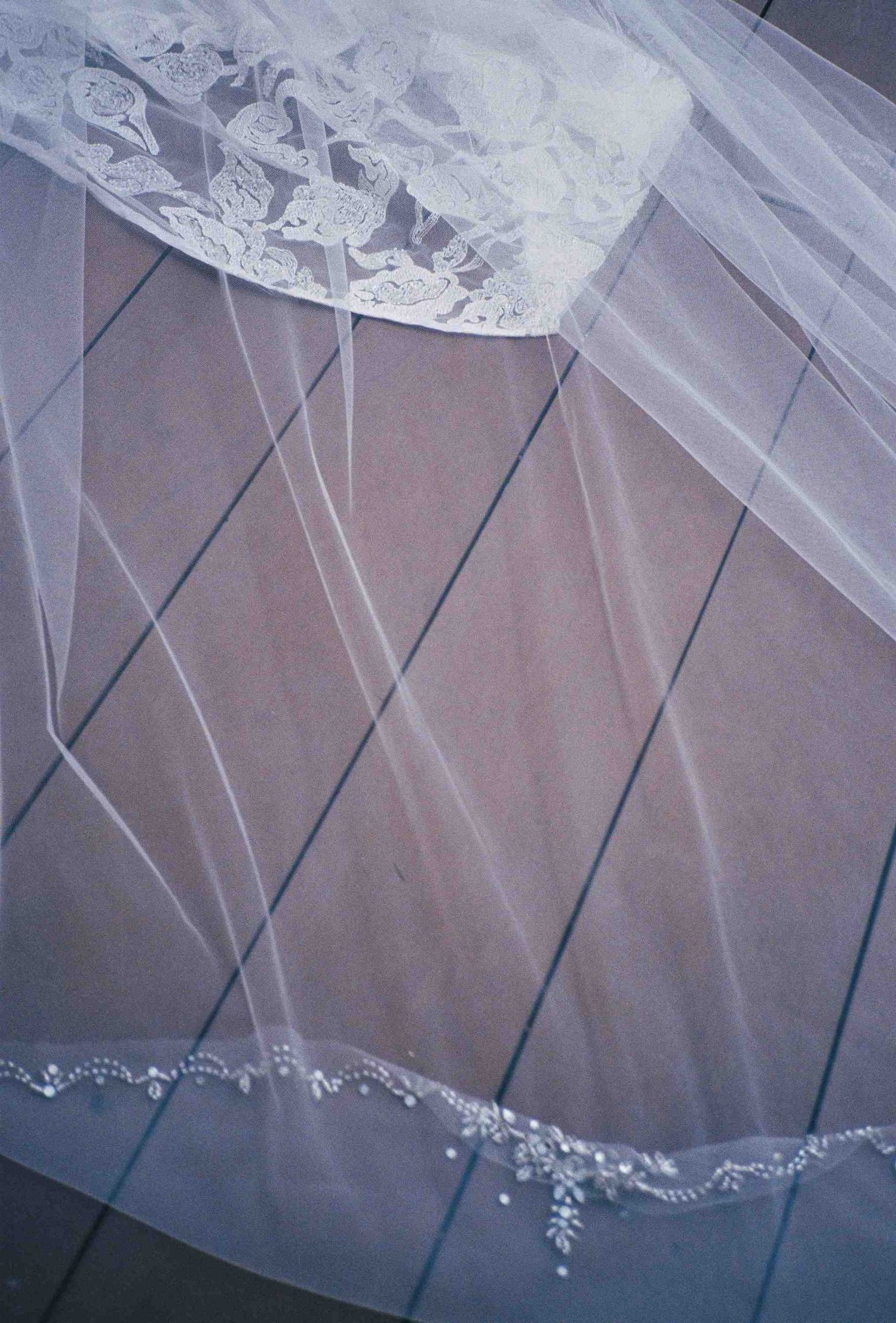 Lang Co wedding: close-up detail of delicate white wedding veil with lace trim and beading, by AnhVuWedding.