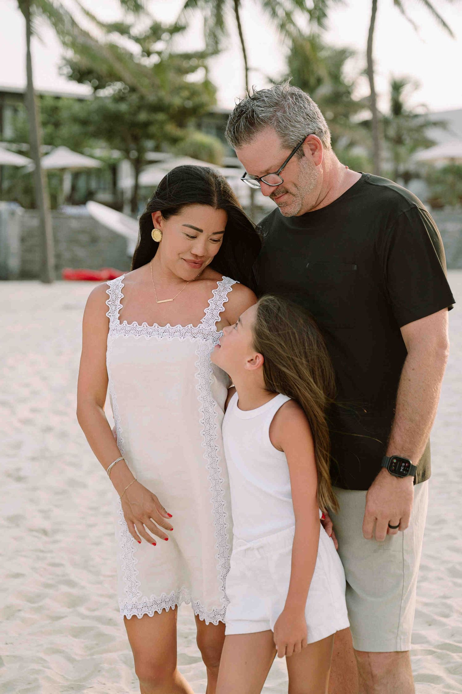 Da Nang family: family sharing tender moments together on a sandy beach during a photo session, by AnhVuWedding.