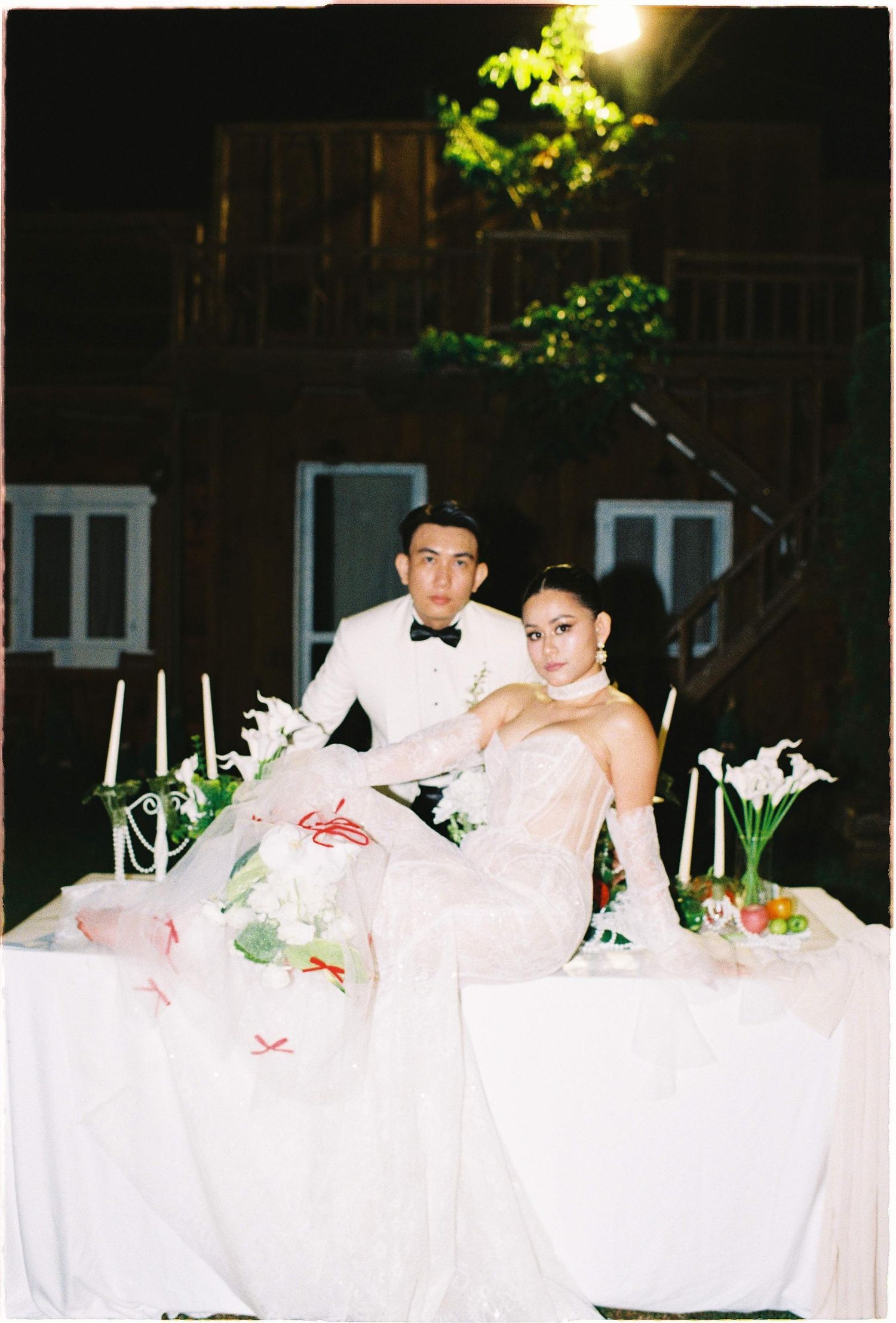 Saigon pre-wedding: elegant wedding couple poses at a romantic outdoor table setting with white linens and calla lily, by AnhVuWedding.