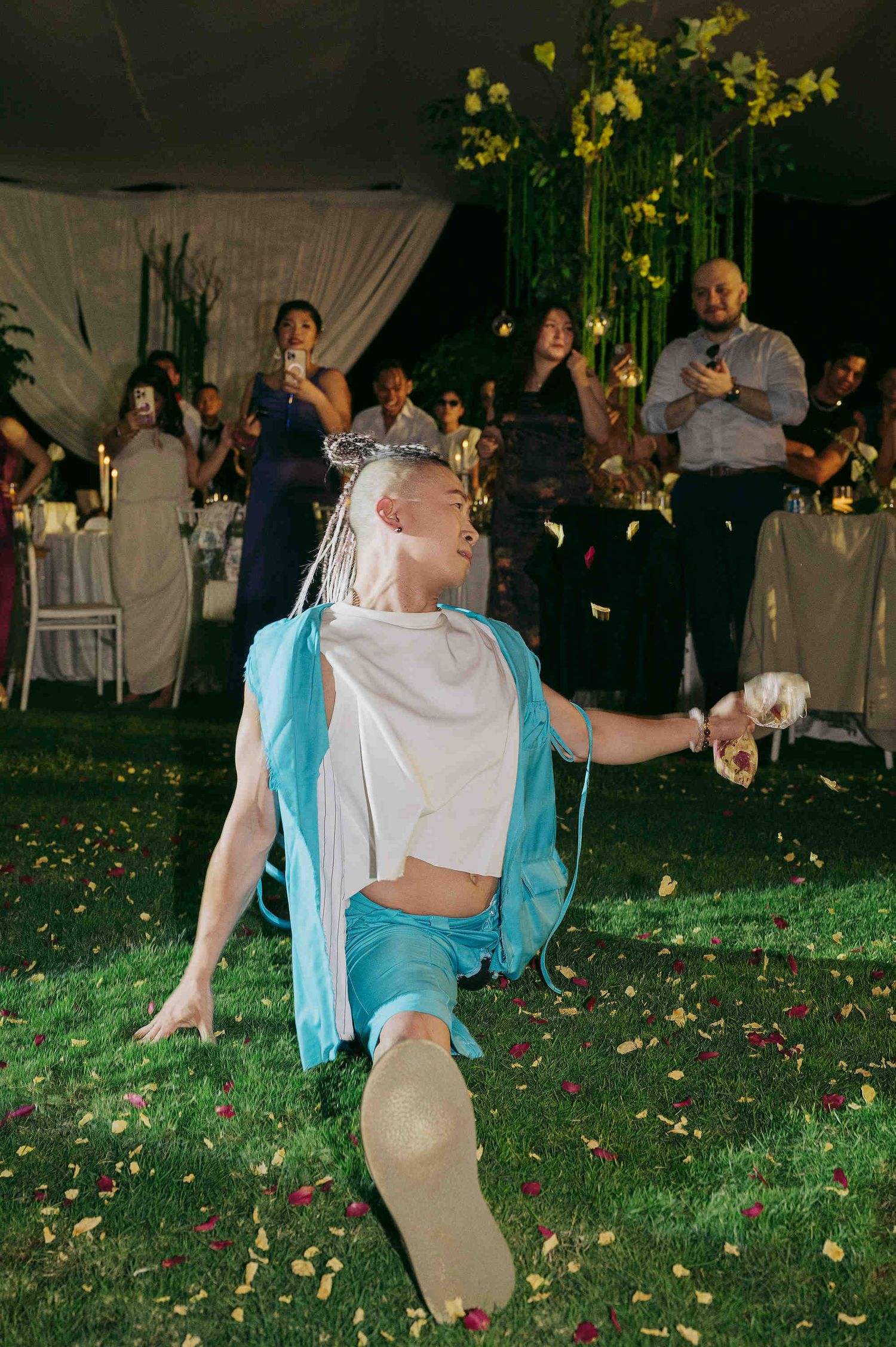 Performer in blue and white costume dancing at an outdoor wedding reception with guests watching.