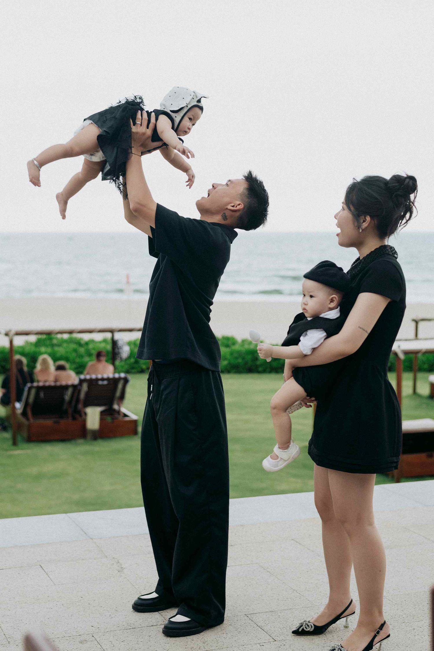 Da Nang family: playful family moment captured outdoors on a beachfront terrace, by AnhVuWedding.