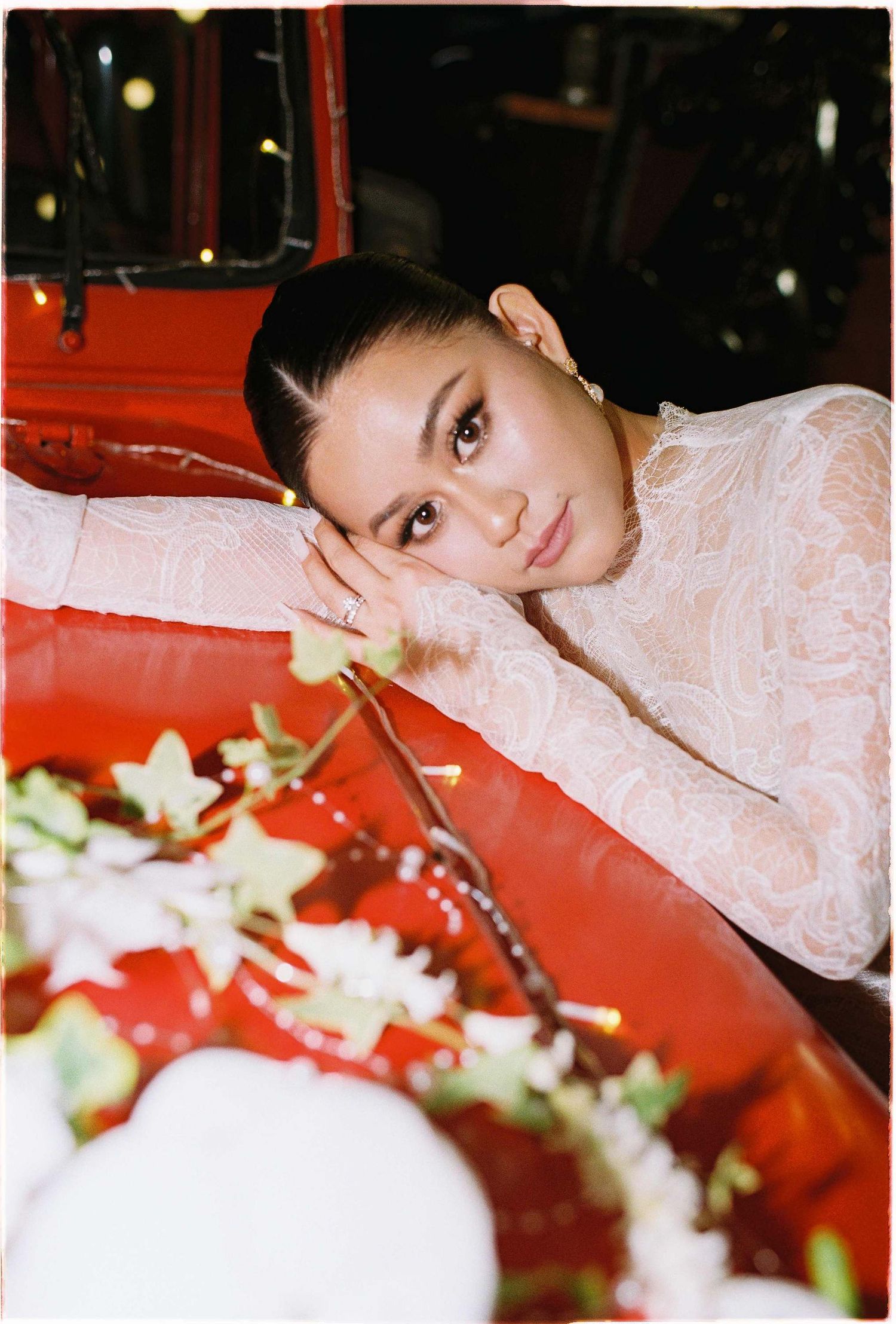 Saigon pre-wedding: elegant bridal portrait against a vibrant red background with white floral decorations, by AnhVuWedding.