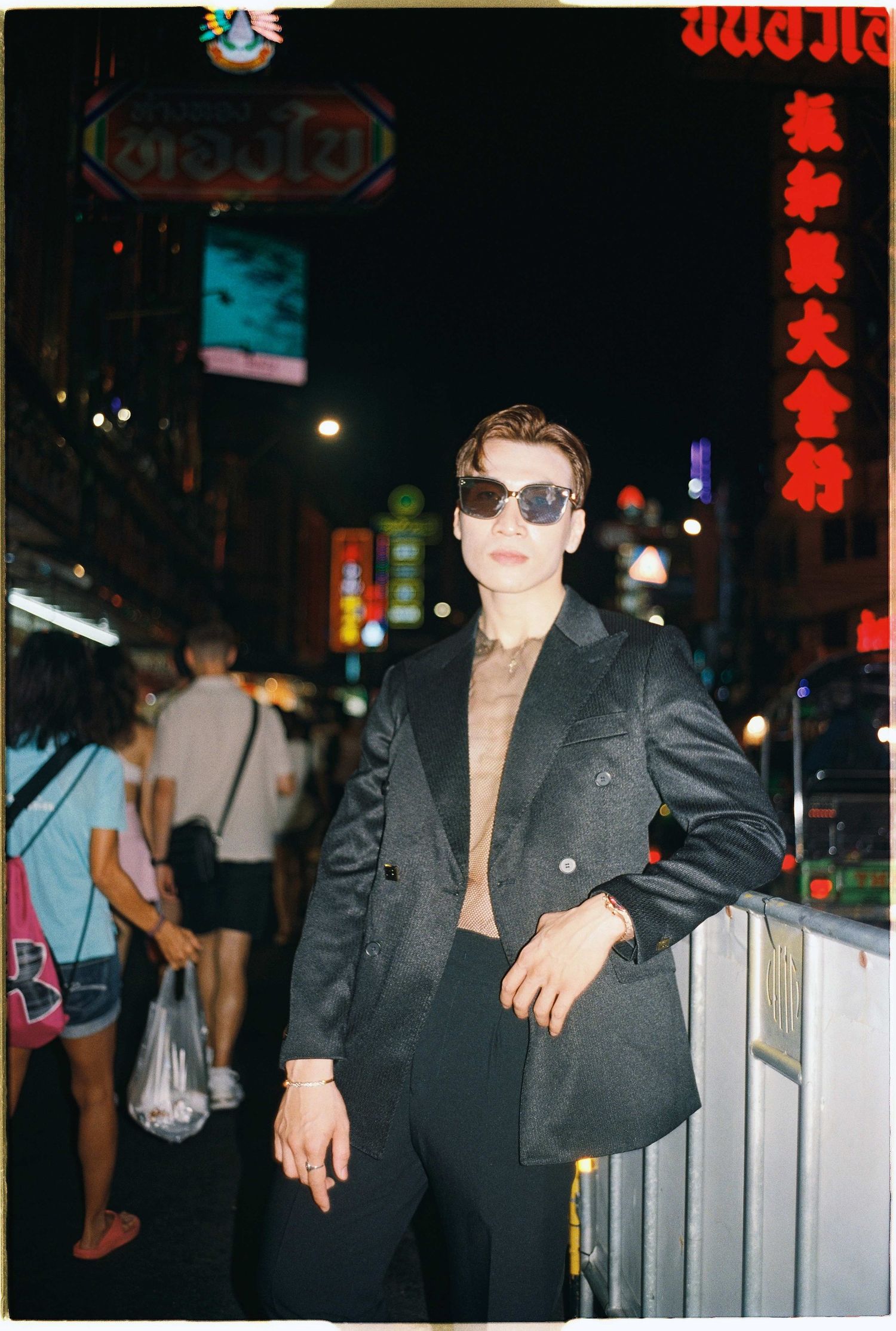 Saigon pre-wedding: nighttime street scene with people wearing black clothing and sunglasses against neon lights, by AnhVuWedding.