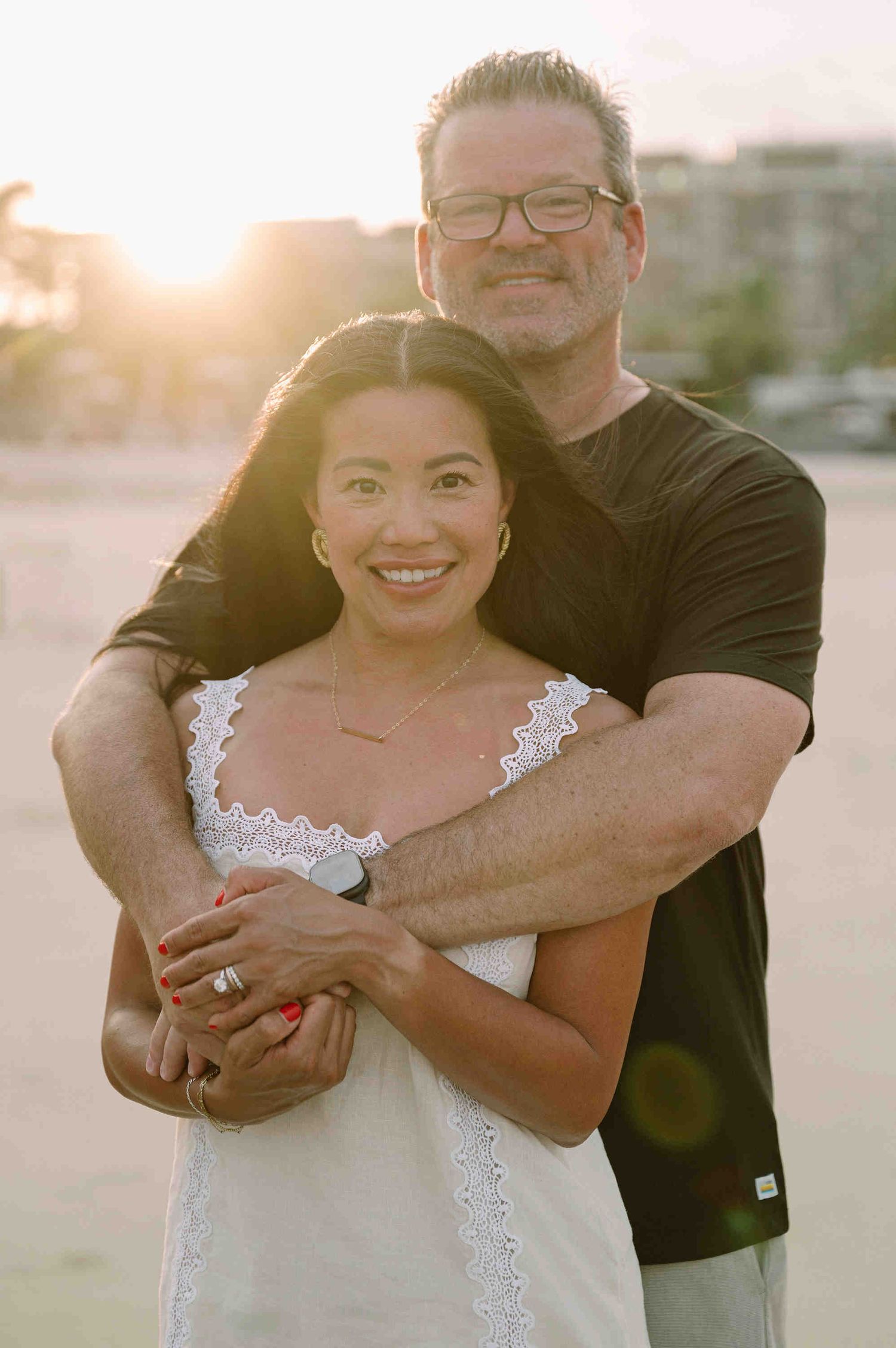 Da Nang family: couple embraces on a beach at sunset, with the person wearing a white lace dress and the other in black, by AnhVuWedding.
