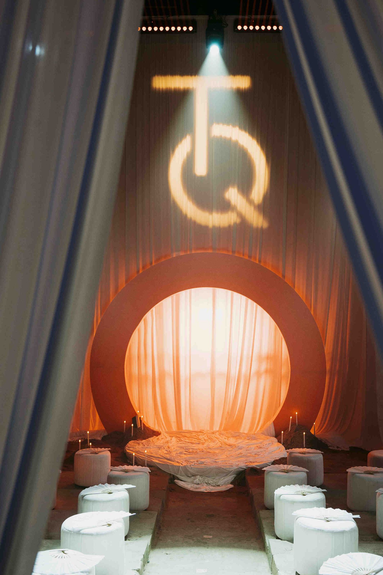 Stunning wedding ceremony venue with orange circular arch, draped curtains, and illuminated monogram above.