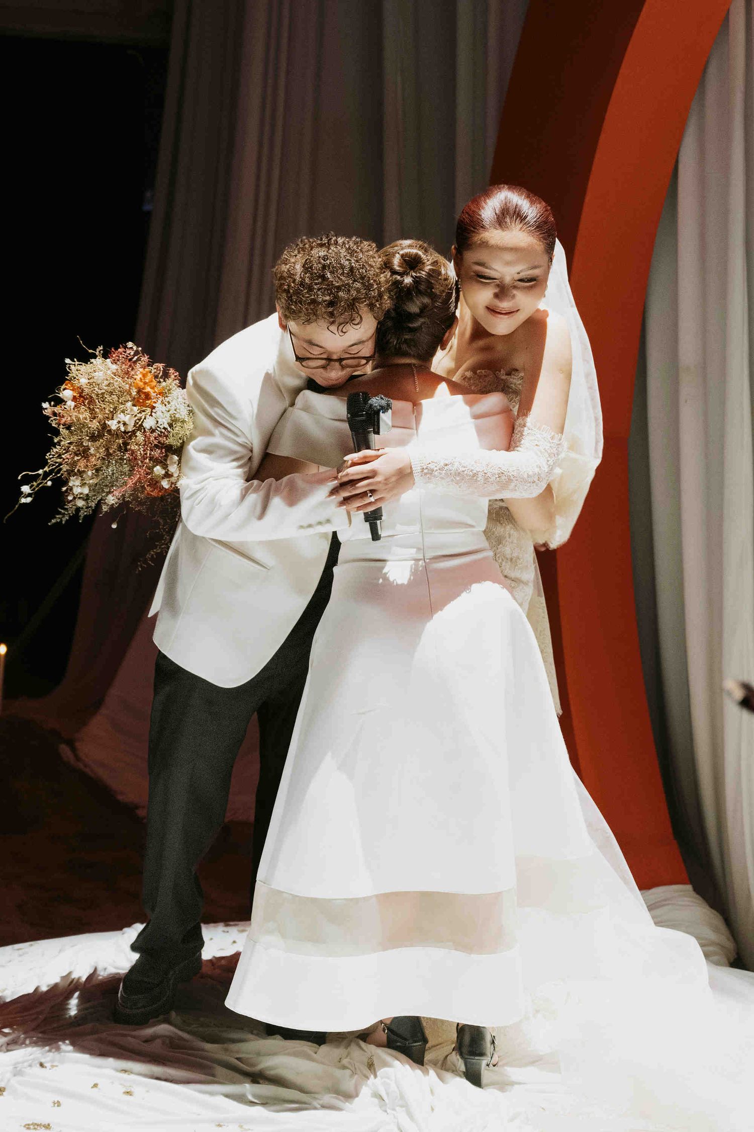 Bride and groom share a tender moment at wedding ceremony, bride in white gown holding bouquet of autumn flowers.