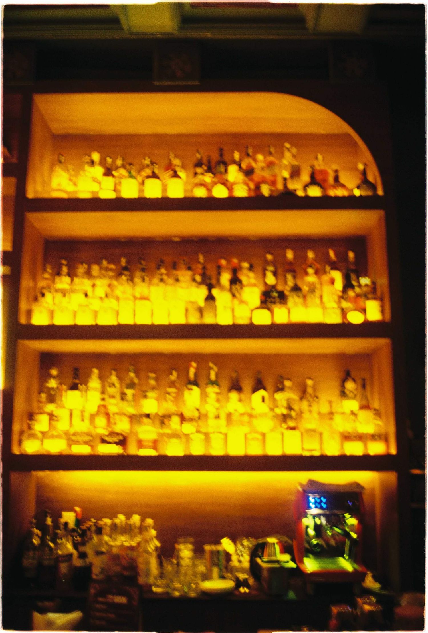 Vietnam pre-wedding: illuminated bar shelves displaying rows of backlit liquor bottles, by AnhVuWedding.