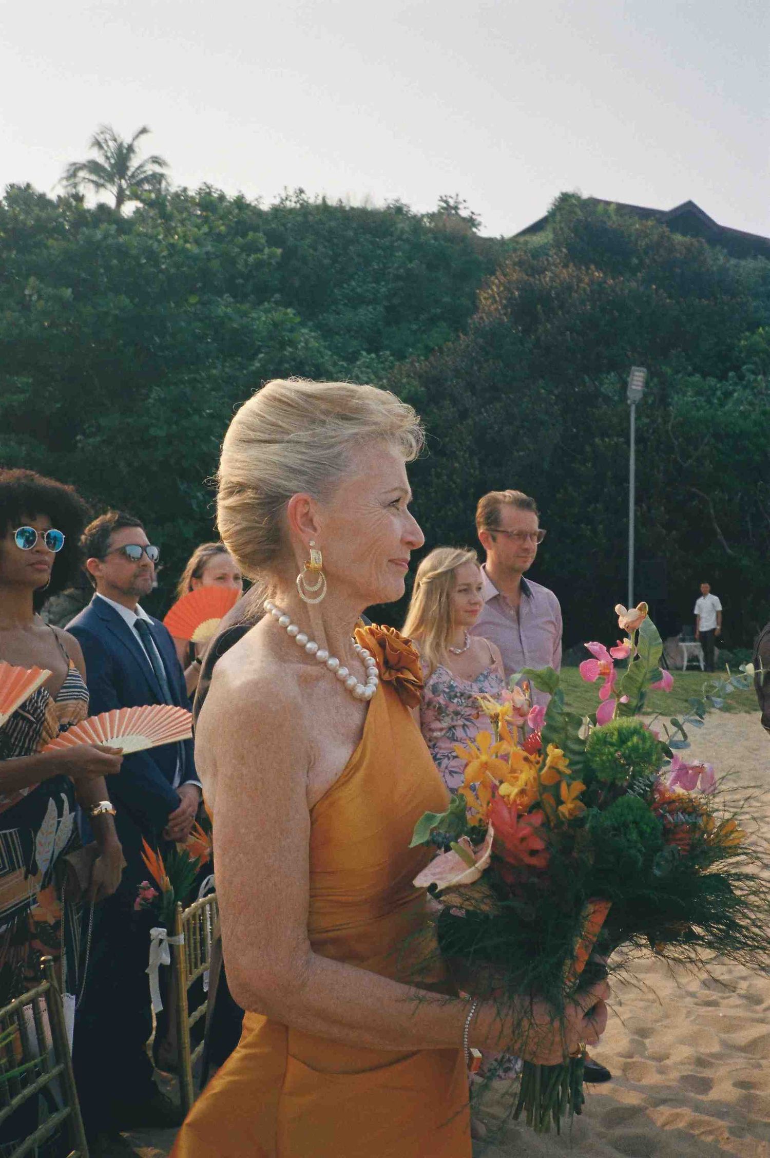 Lang Co wedding ceremony: wedding guests enjoy a beach ceremony at sunset with colorful floral arrangements, by AnhVuWedding.