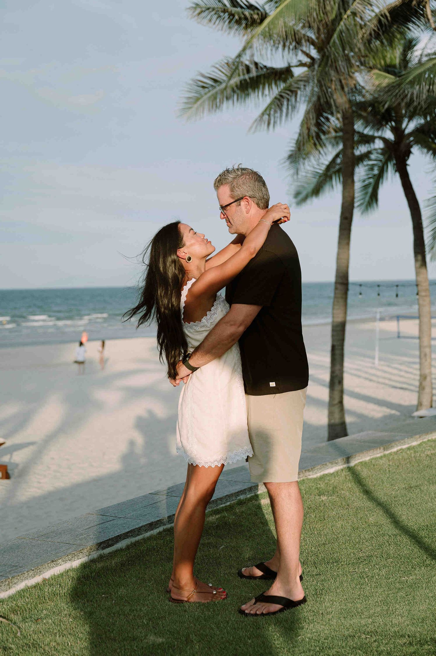 Da Nang family: couple shares a romantic kiss on a grassy beachfront area, by AnhVuWedding.