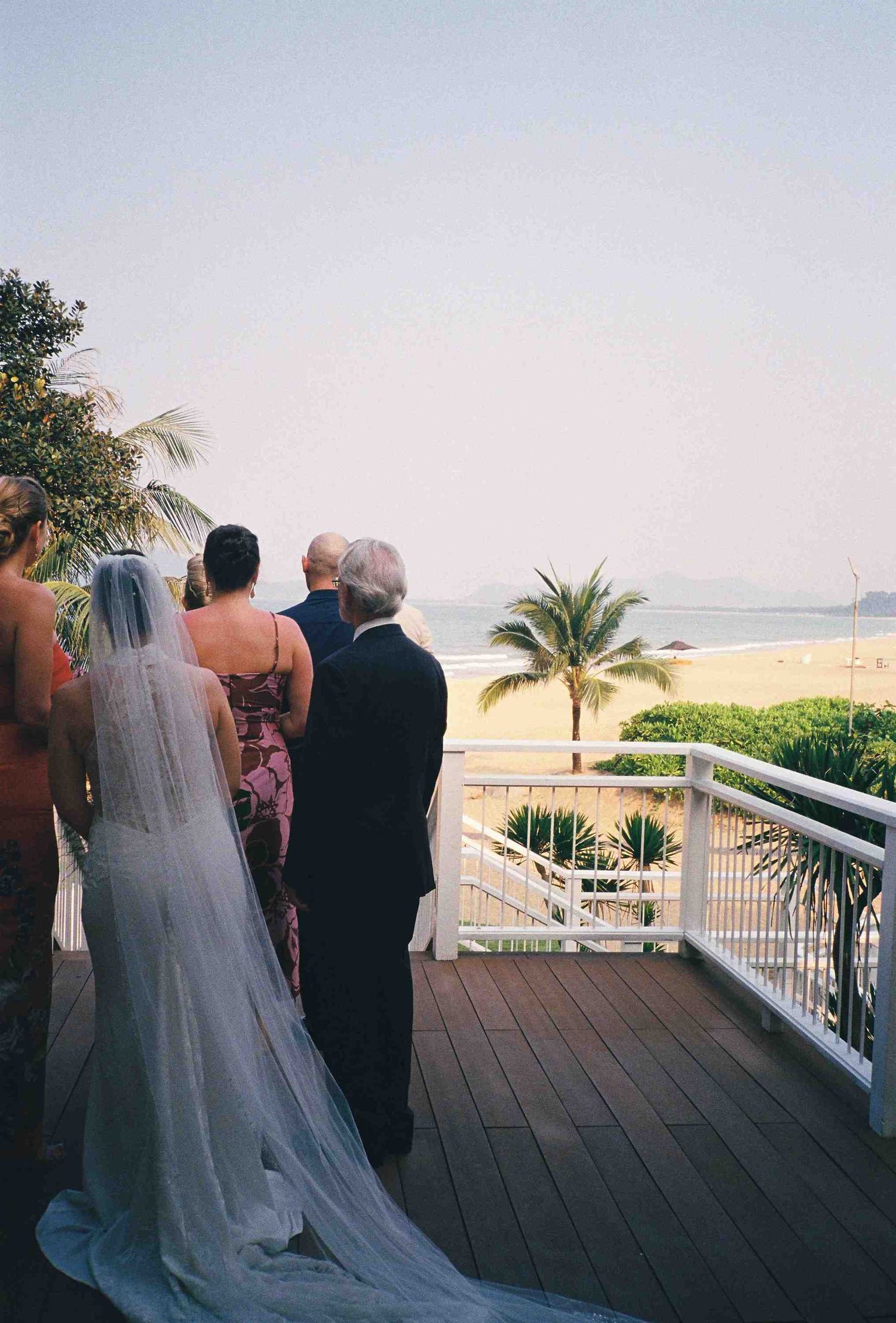 Lang Co wedding ceremony: wedding ceremony on oceanfront deck with palm trees and beach views, by AnhVuWedding.