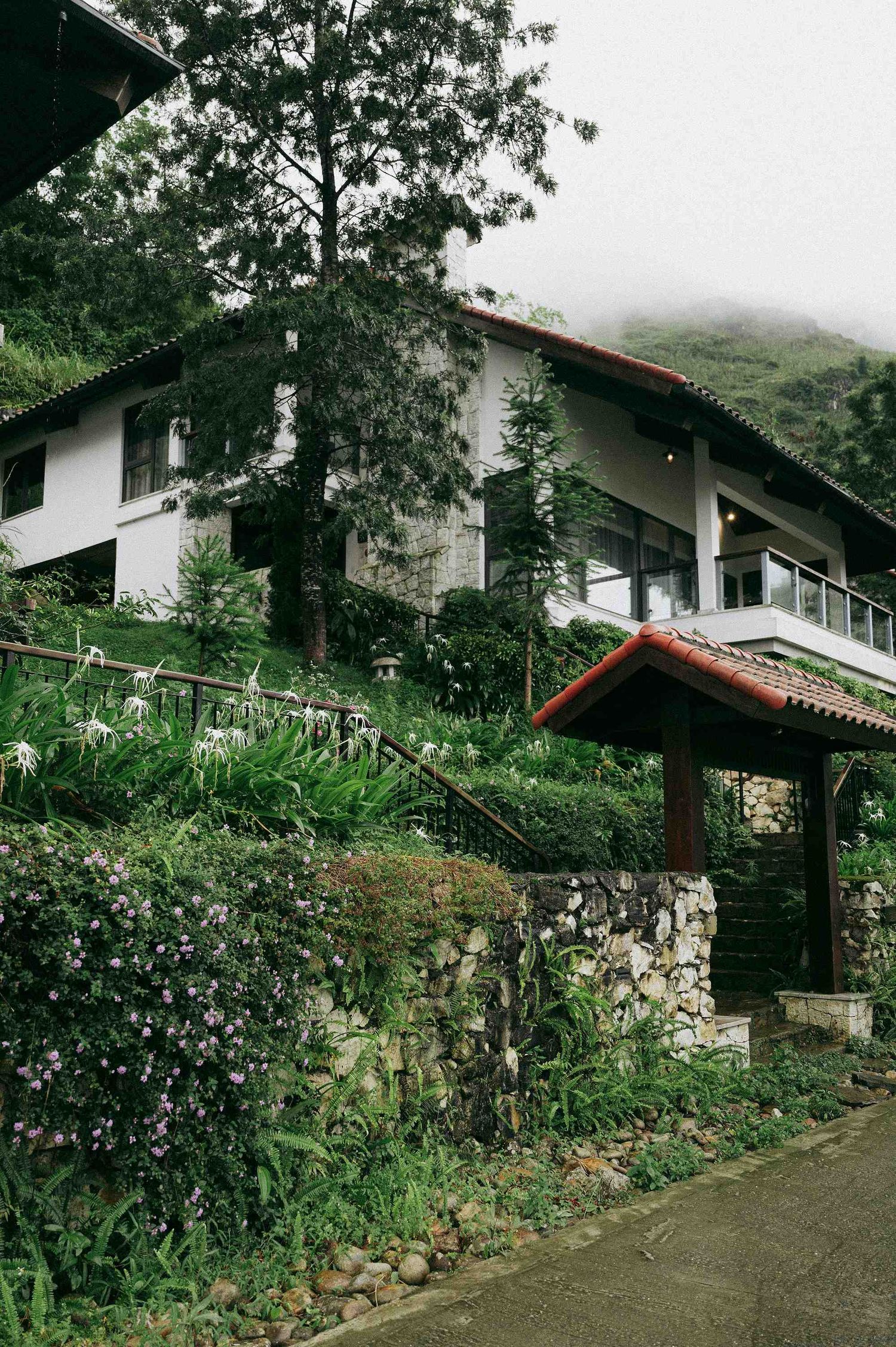 wedding: white mountain villa with red tile roof nestled among lush greenery and stone walls, by AnhVuWedding.