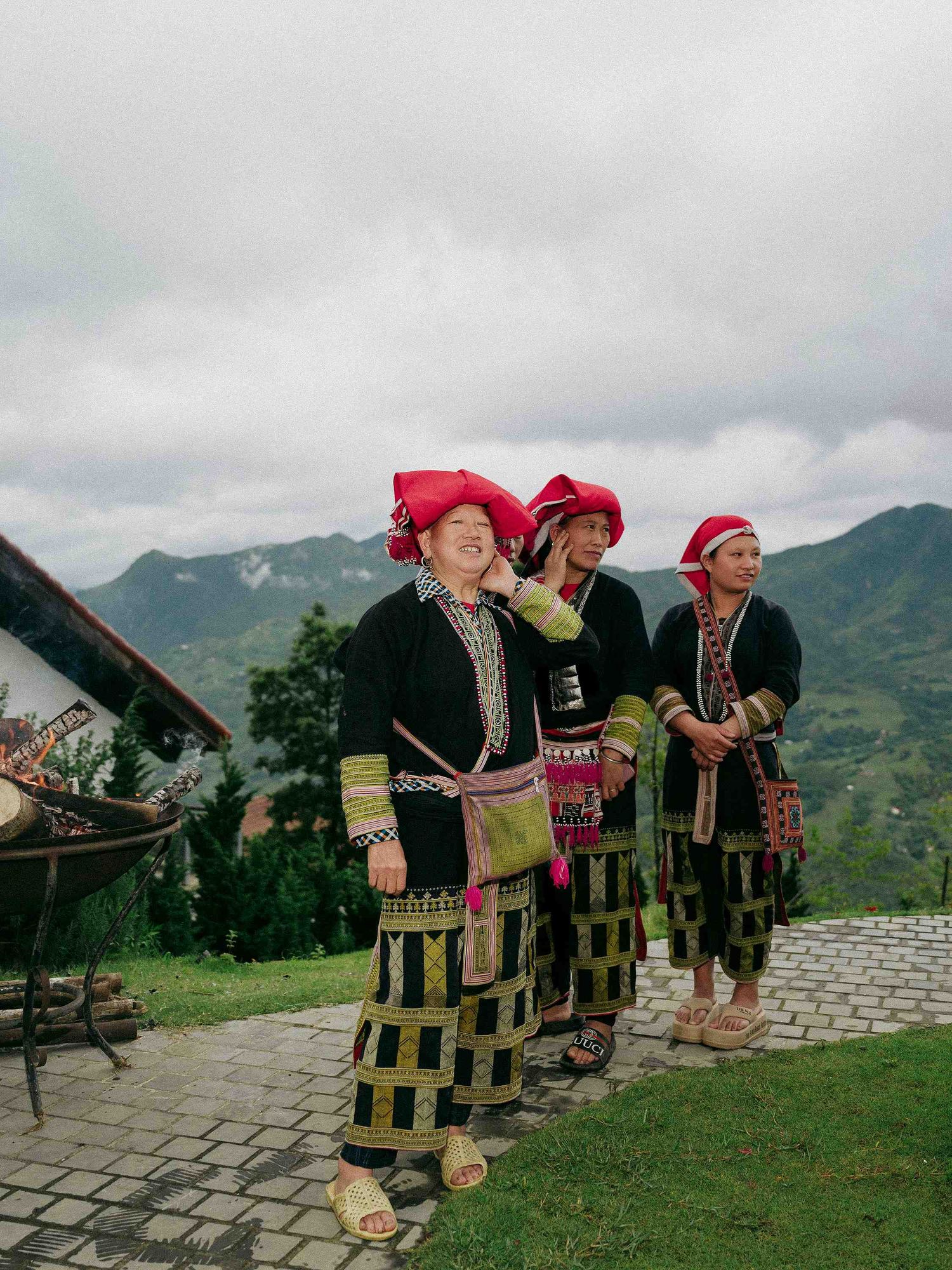 wedding: three women in traditional hill tribe costumes with red headdresses standing on mountain viewpoint, by AnhVuWedding.