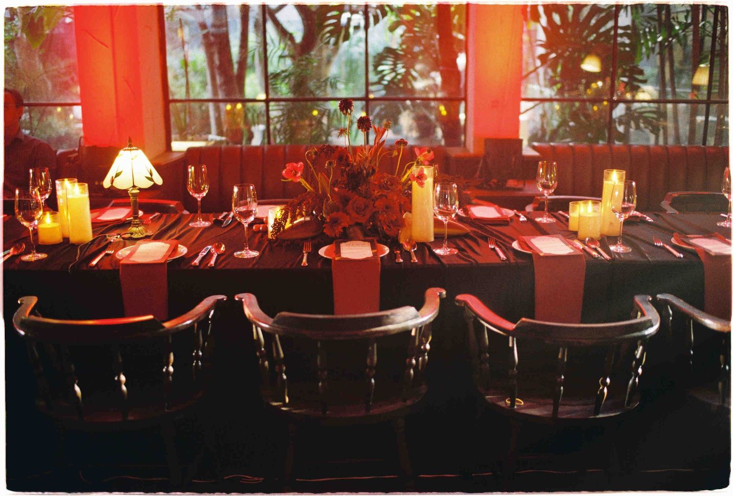 Elegant restaurant dining table set for a formal event with candles, wine glasses, and red ambient lighting.