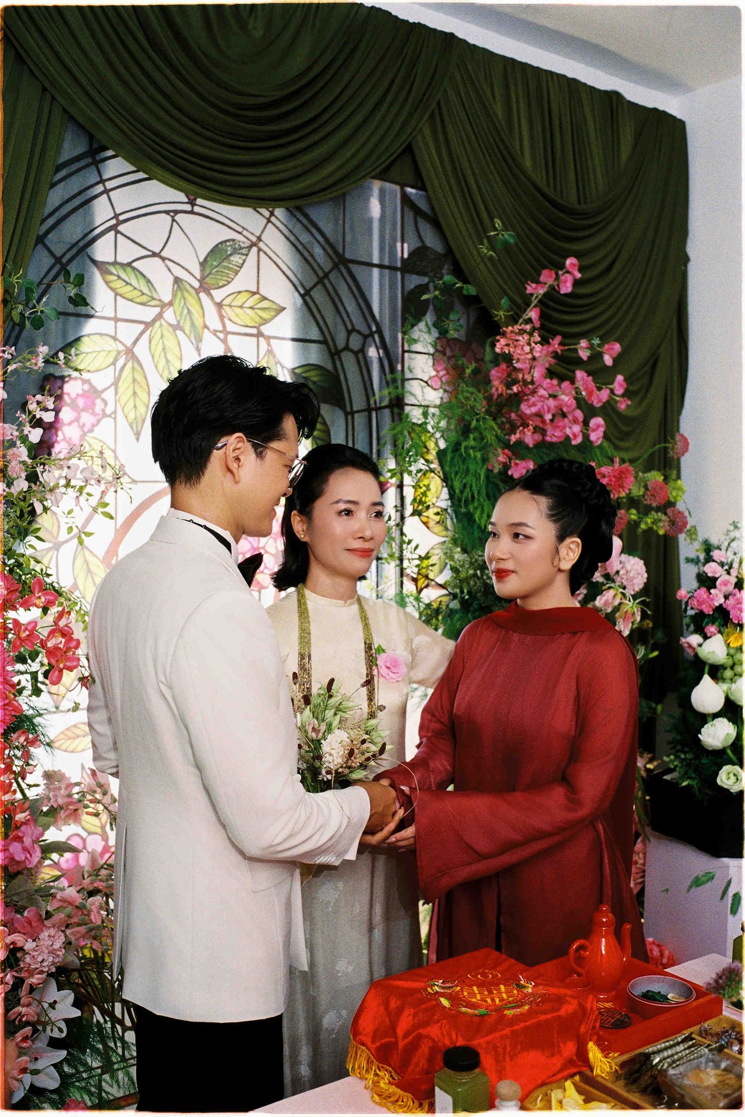 Vietnamese wedding ceremony with couple in traditional ao dai attire exchanging vows amid floral decorations.