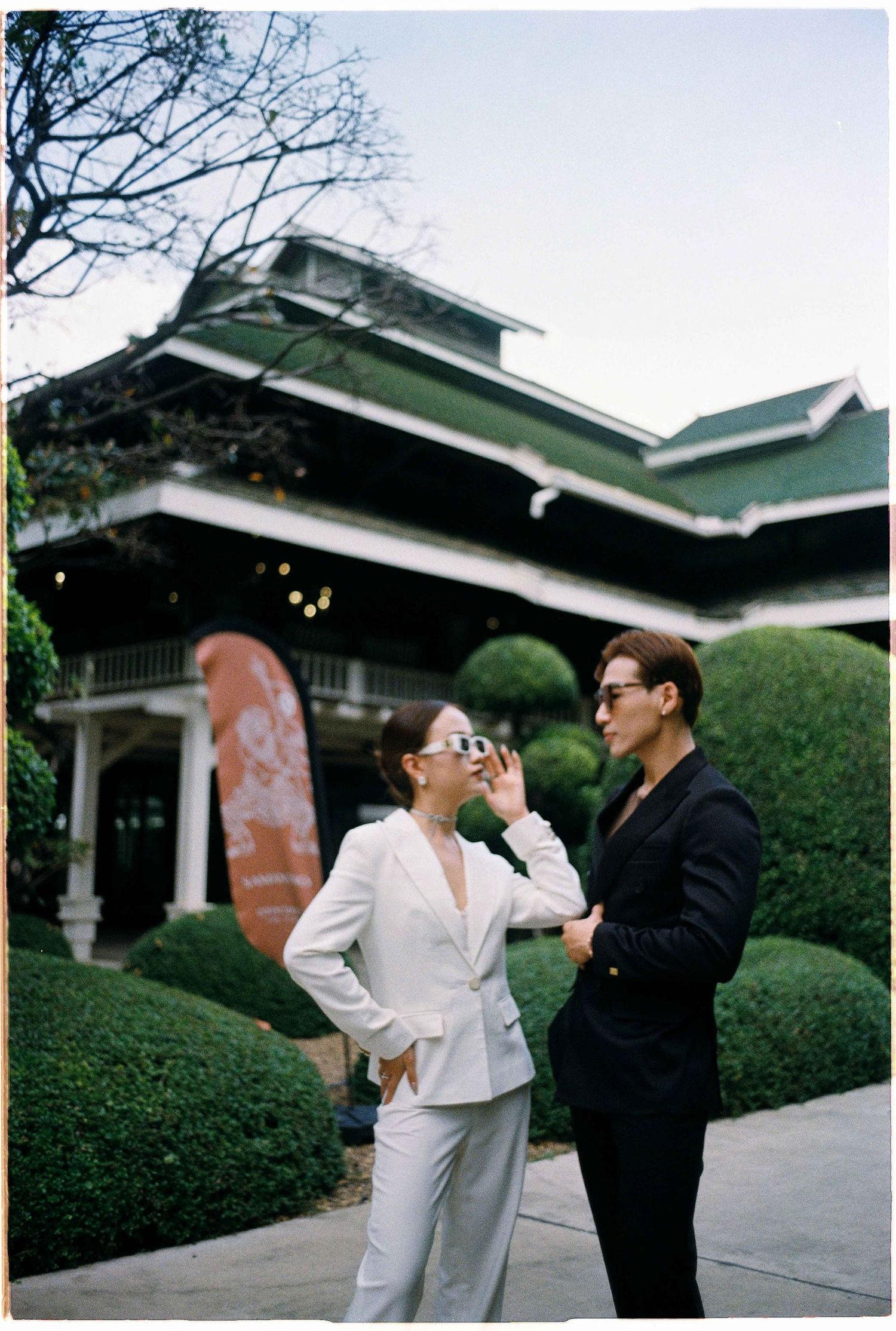 Saigon pre-wedding: stylish couple in black and white outfits pose playfully in front of a traditional building, by AnhVuWedding.