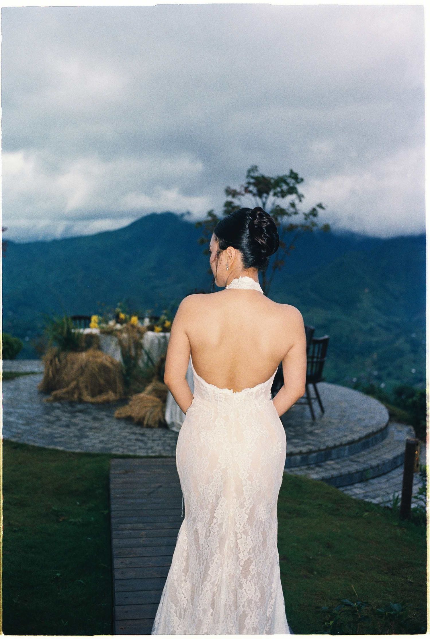 wedding: wedding dress detail against mountain landscape with cloudy sky, by AnhVuWedding.
