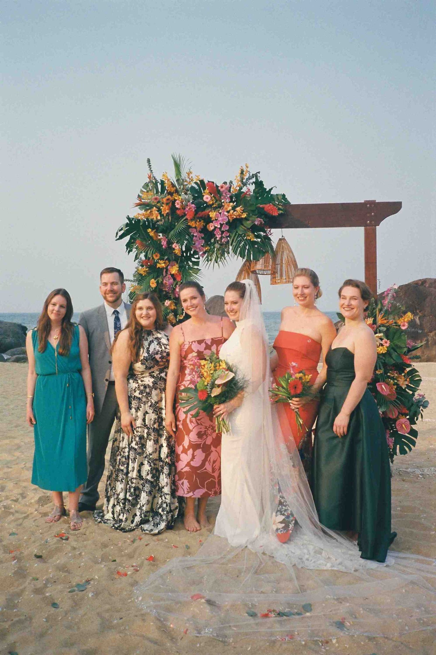 Lang Co wedding: wedding party group photo on beach with bridesmaids in colorful dresses, by AnhVuWedding.