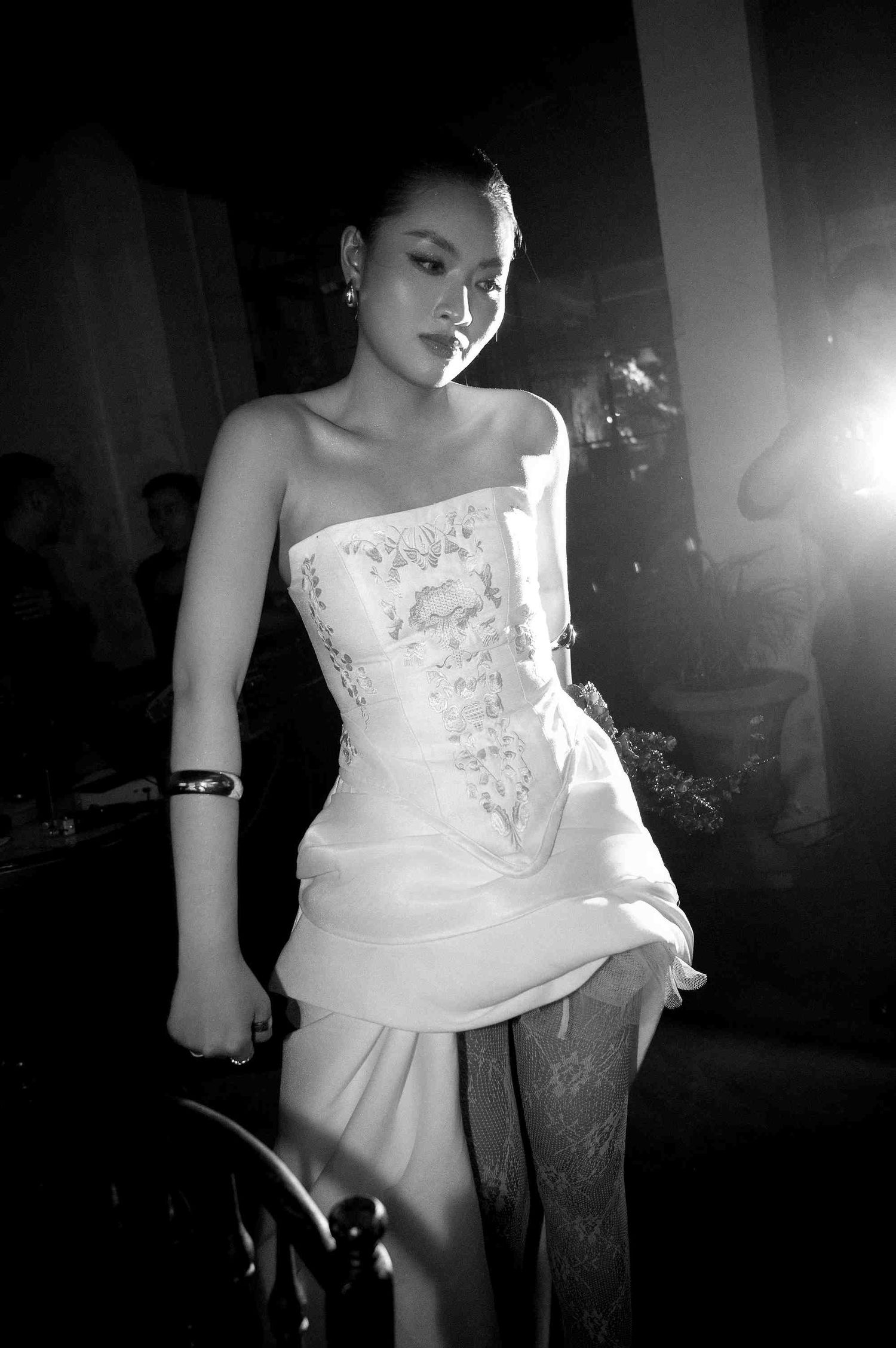 Elegant woman in white strapless corset gown posing at formal event in black and white photo.
