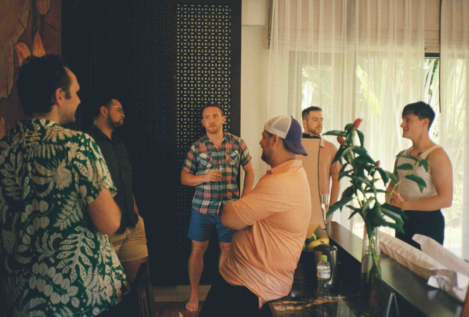 Lang Co wedding: group of people gather in a hotel room during preparations, with someone adjusting a plant, by AnhVuWedding.